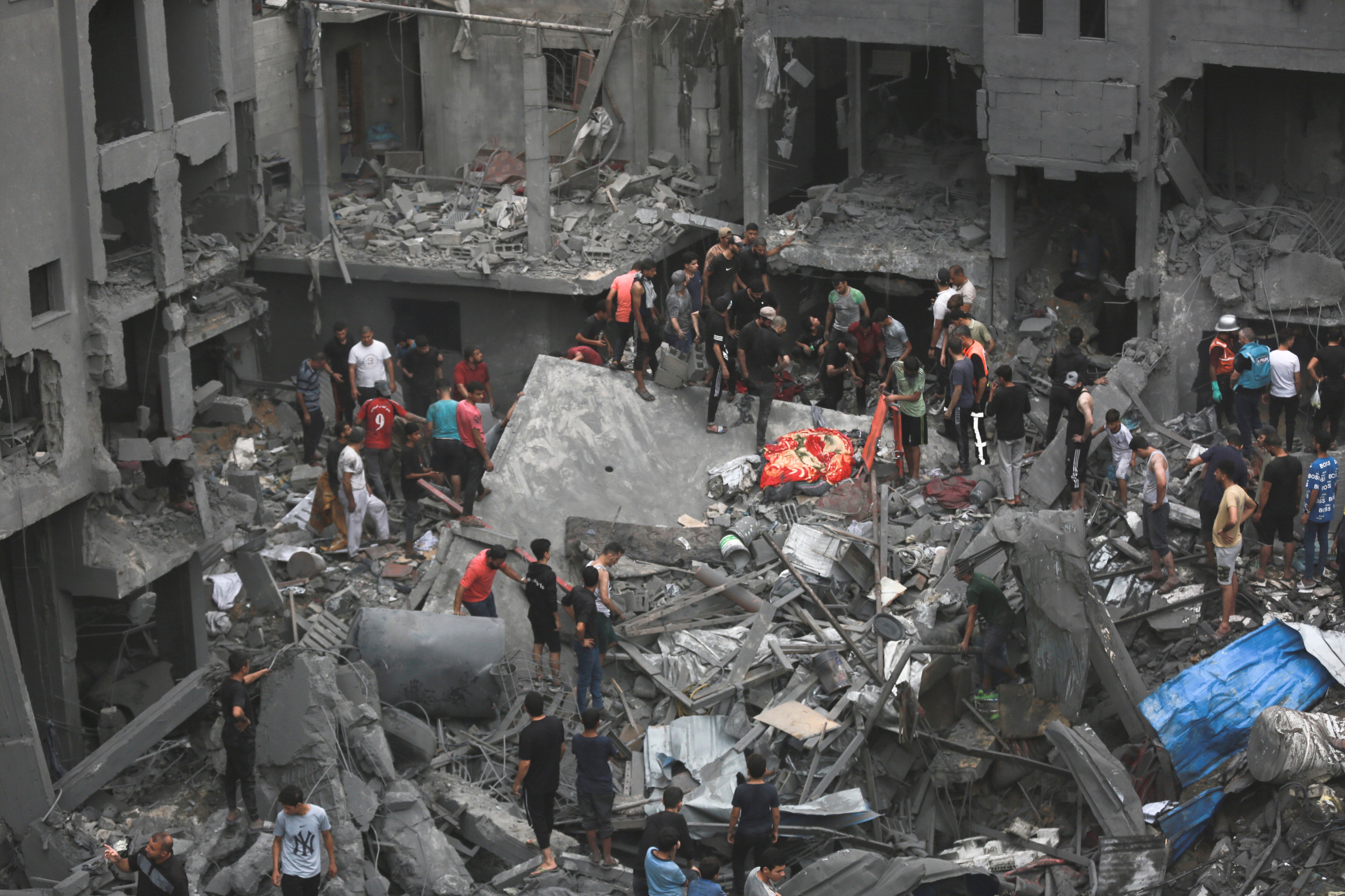 Palestinians stand amid the ruins of a building in Gaza City after it was bombed by Israel
