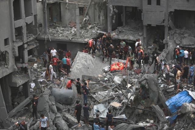 <p>Palestinians stand amid the ruins of a building in Gaza City after it was bombed by Israel </p>