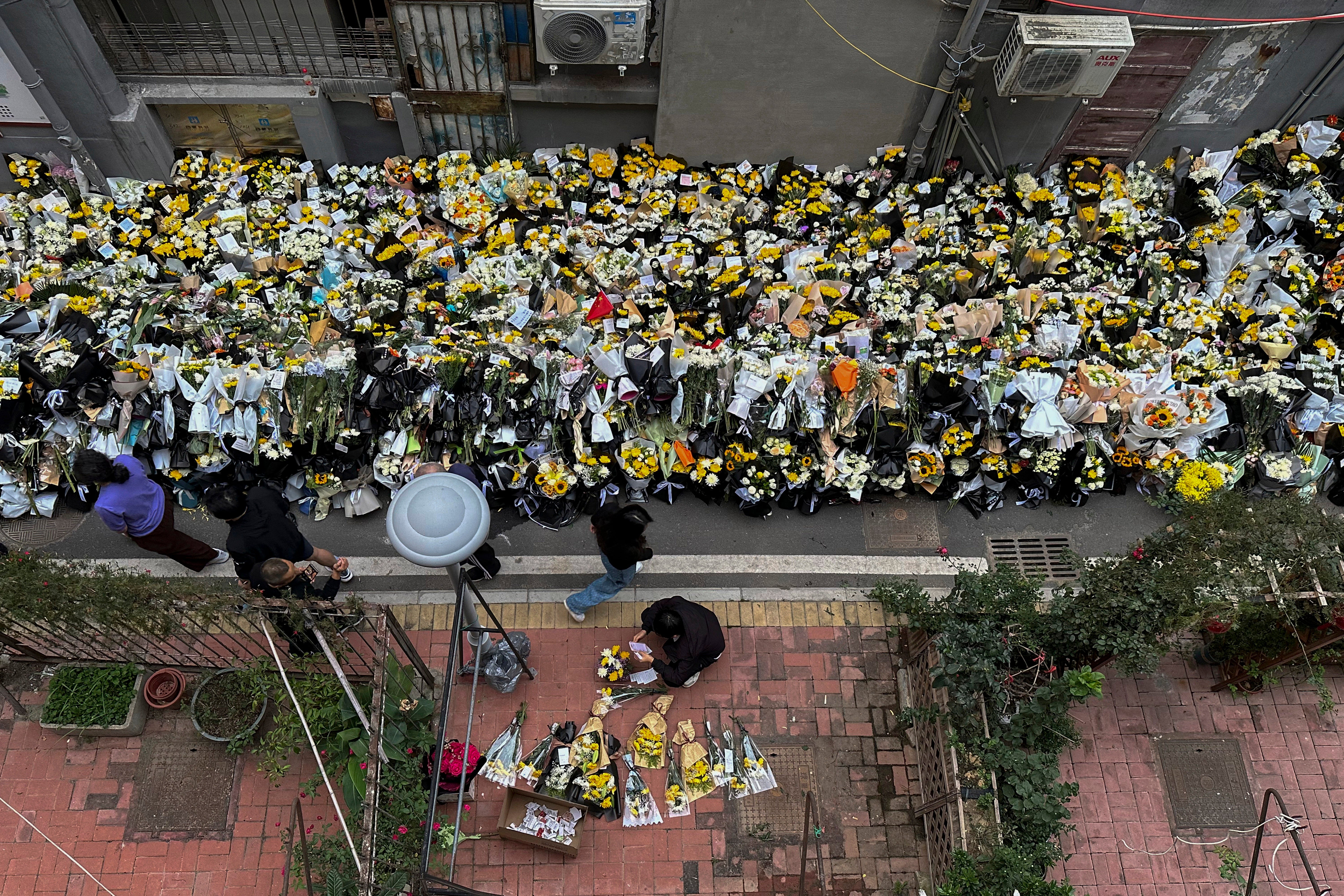 Residents walk by flowers laid outside a residential building where Li Keqiang spent his childhood in Hefei city