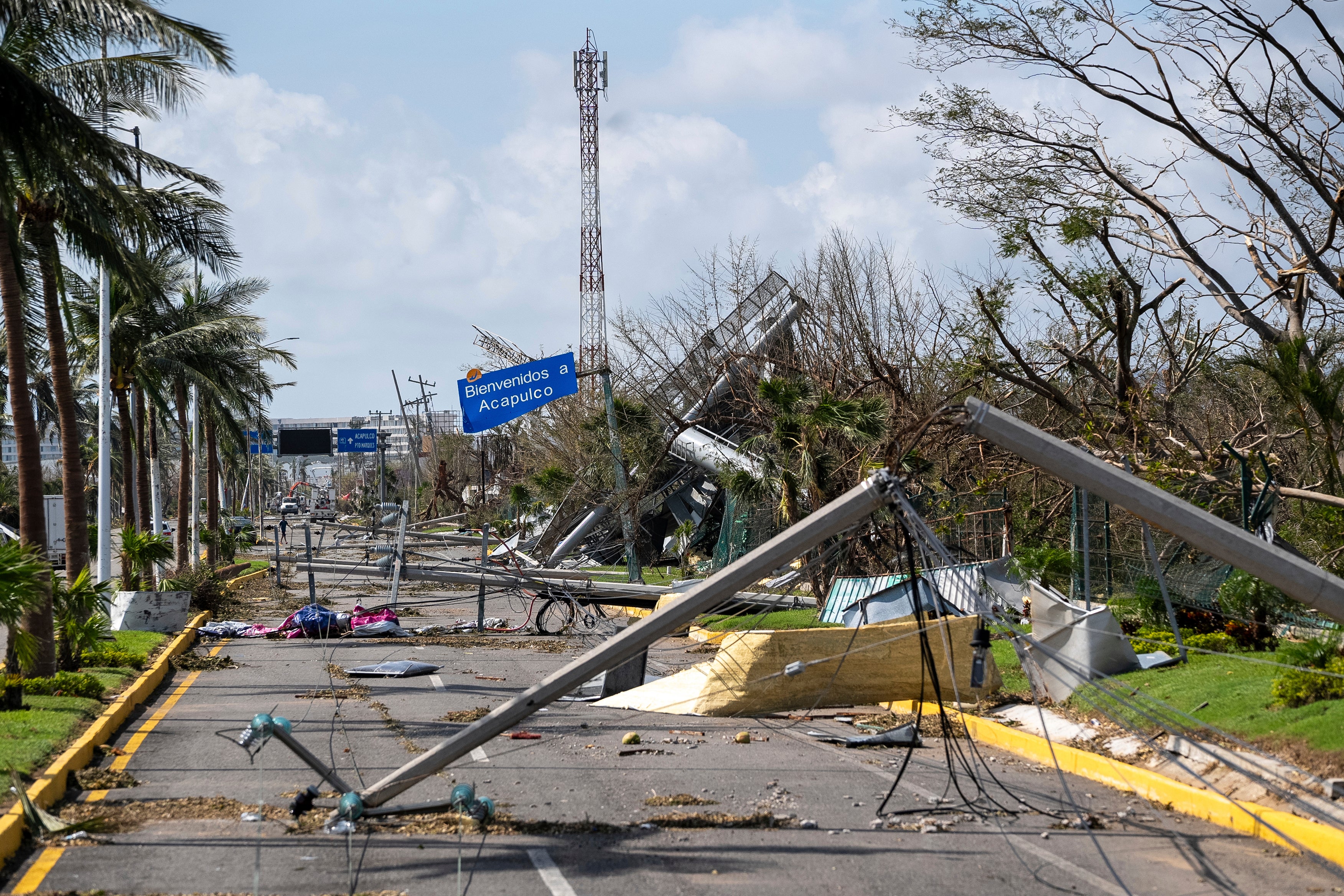 Downed electrical poles and lines blown over by Hurricane Otis blanket a road in Acapulco