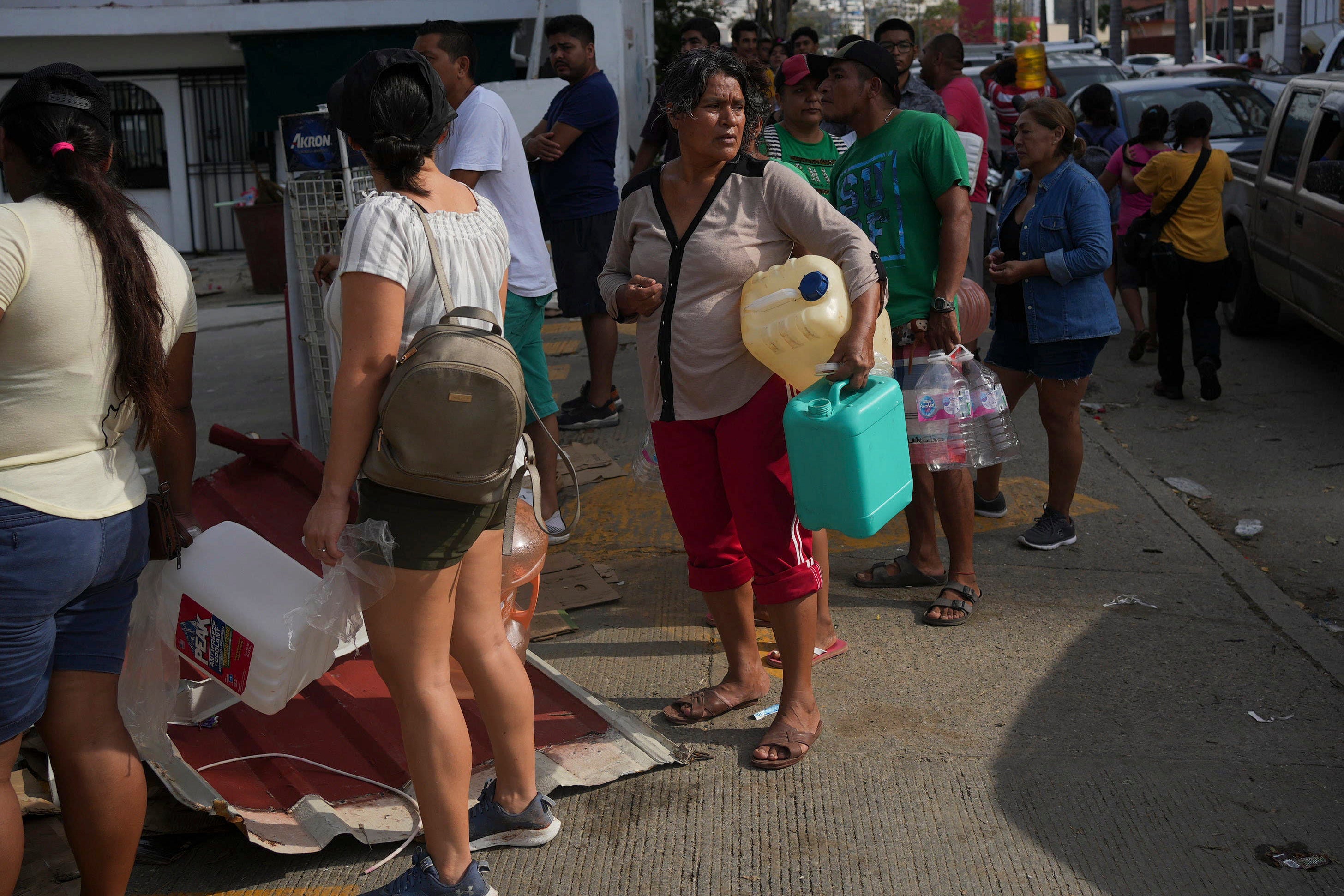 People wait in line with containers to buy gasoline in Acapulco
