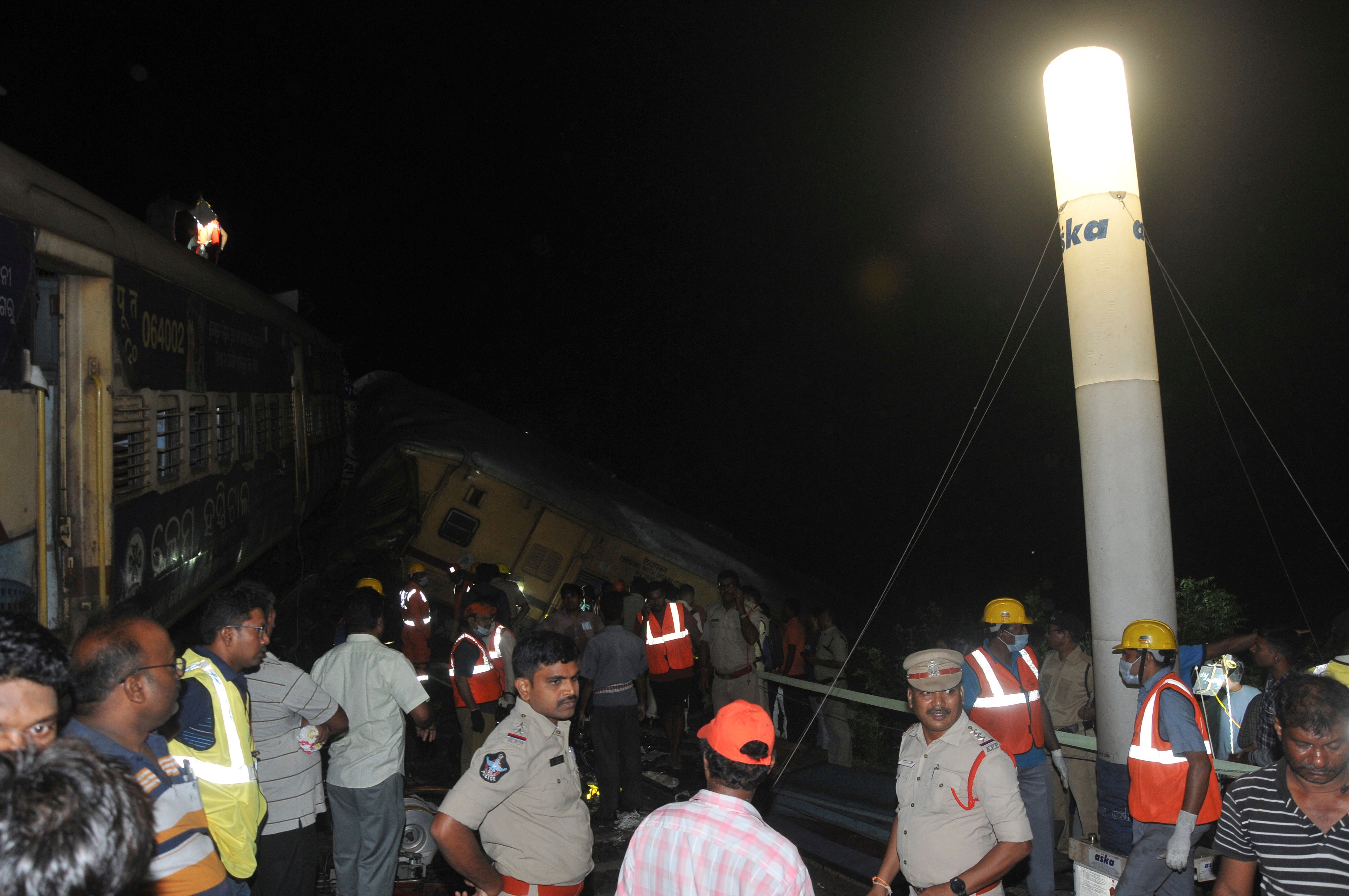 Rescuers and others stand after two passenger trains collided in Vizianagaram district