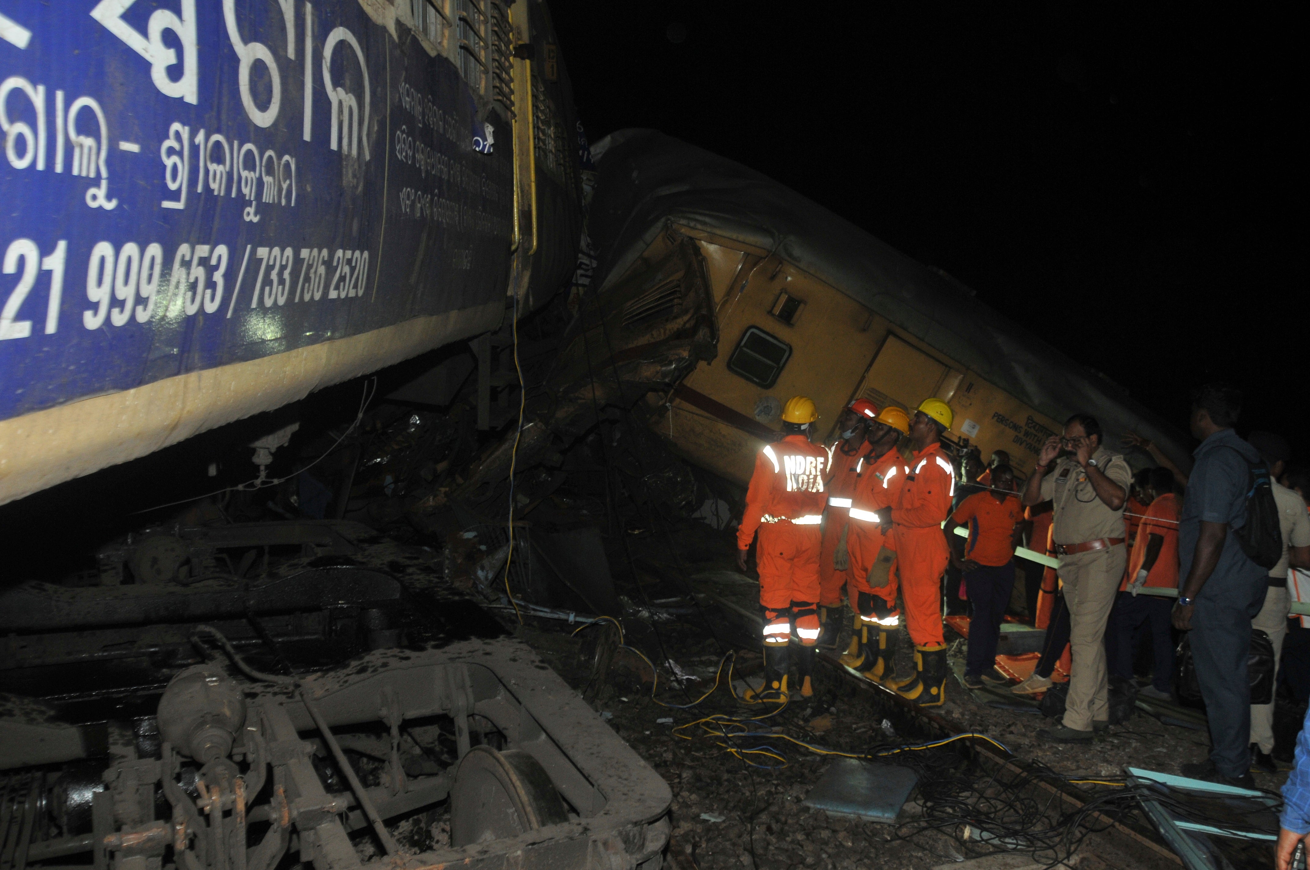 Rescuers and others stand after two passenger trains collided in Vizianagaram district