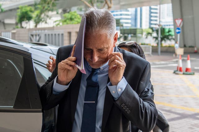 <p>Washington state senator Jeff Wilson covers himself as he arrives at West Kowloon Magistrates Courts in Hong Kong</p>