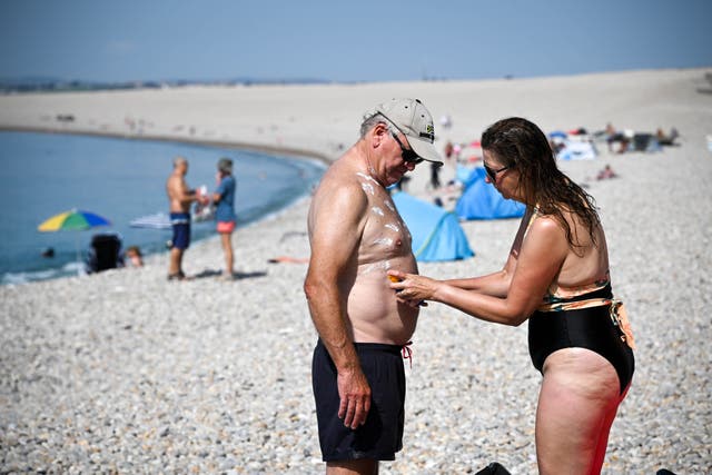<p>Beachgoers apply suncream as theyenjoy the hot weather at Chesil beach, on September 09, 2023 in Portland, England</p>