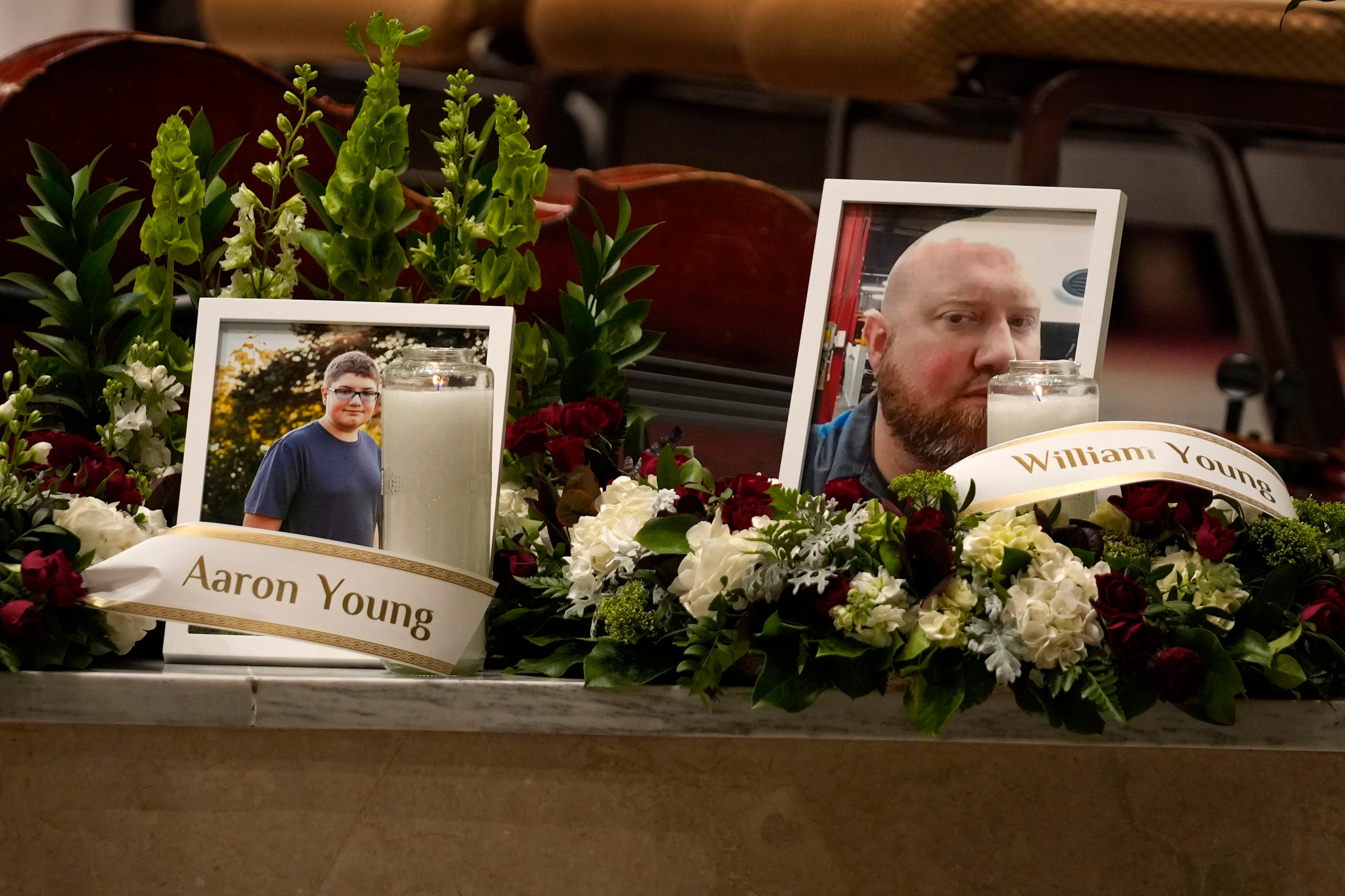 Photos of Aaron Young and his father, William Young, are displayed at a vigil for the victims of Wednesday's mass shootings at the Basilica of Saints Peter and Paul, Sunday, Oct. 29, 2023, in Lewiston, Maine.