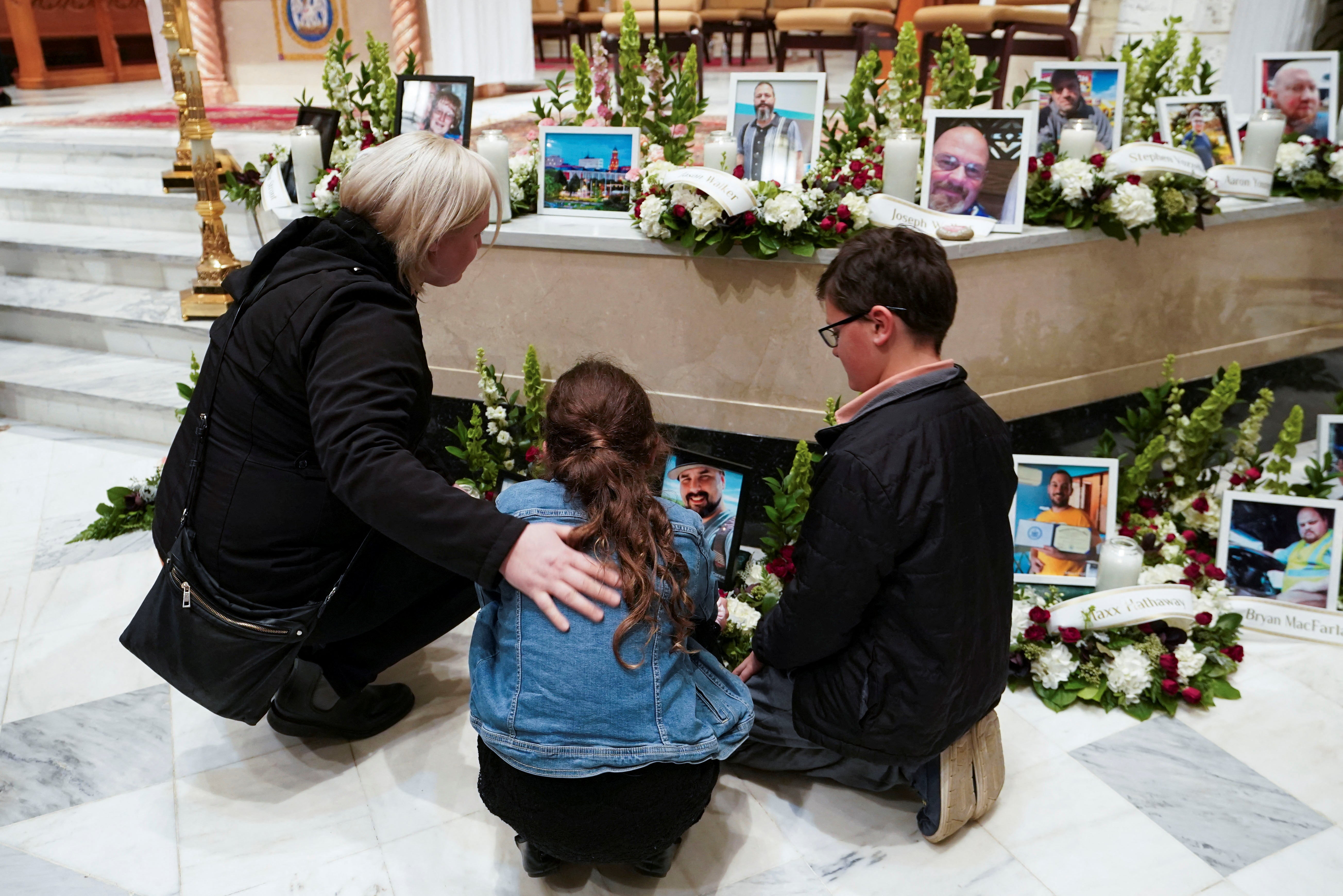 Mourners look at pictures of the victims during a vigil for the victims of the deadly mass shooting, at the Basilica of Saints Peter and Paul, in Lewiston, Maine