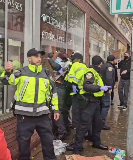 Police are seen restraining a protestor outside the headquarters of Elbit Systems in Boston