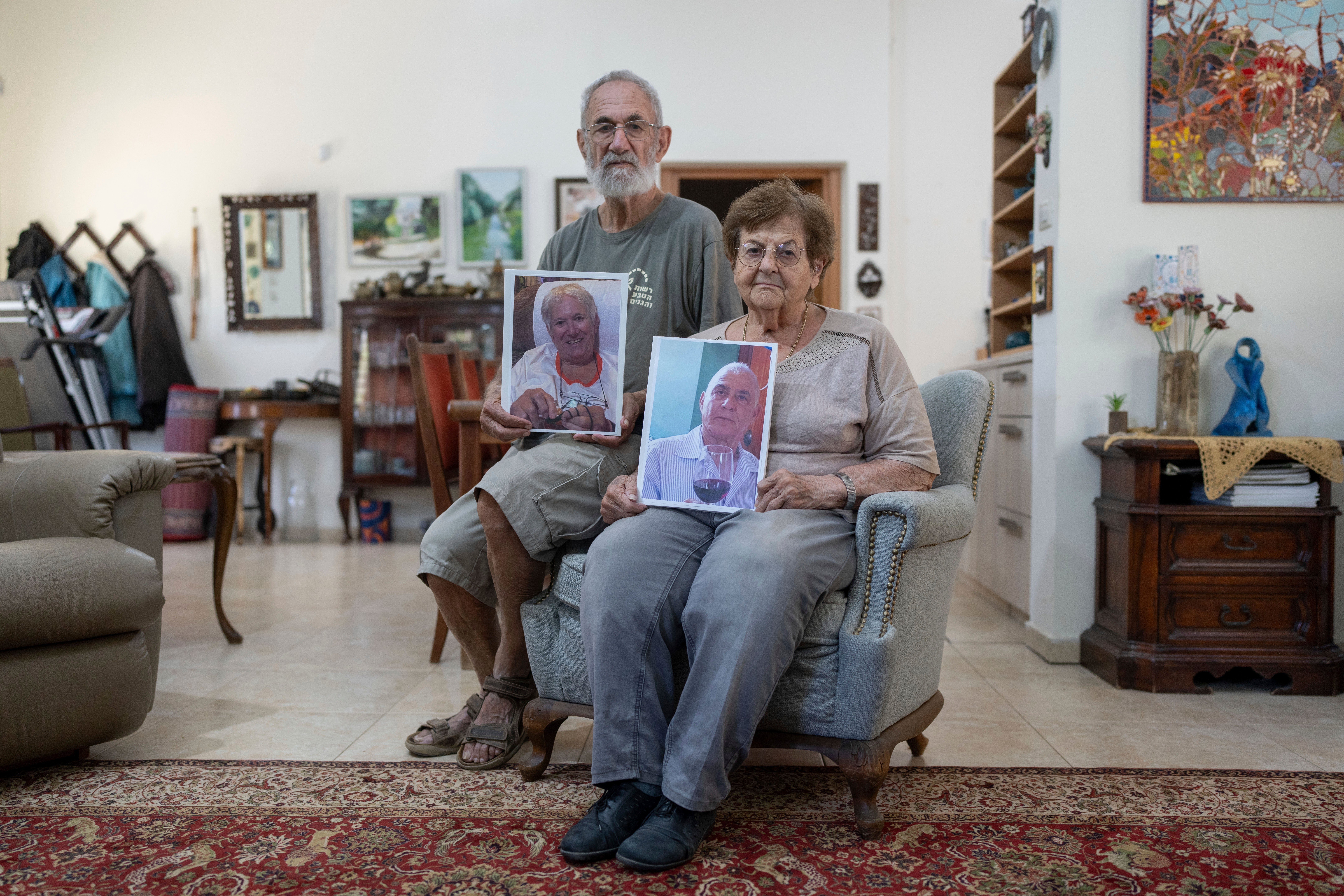 Chanan Choen, along with his wife, Edna Choen, hold up portraits of his sister, 77-year-old Margalit Moses, and her husband, 79-year-old Gadi Moses