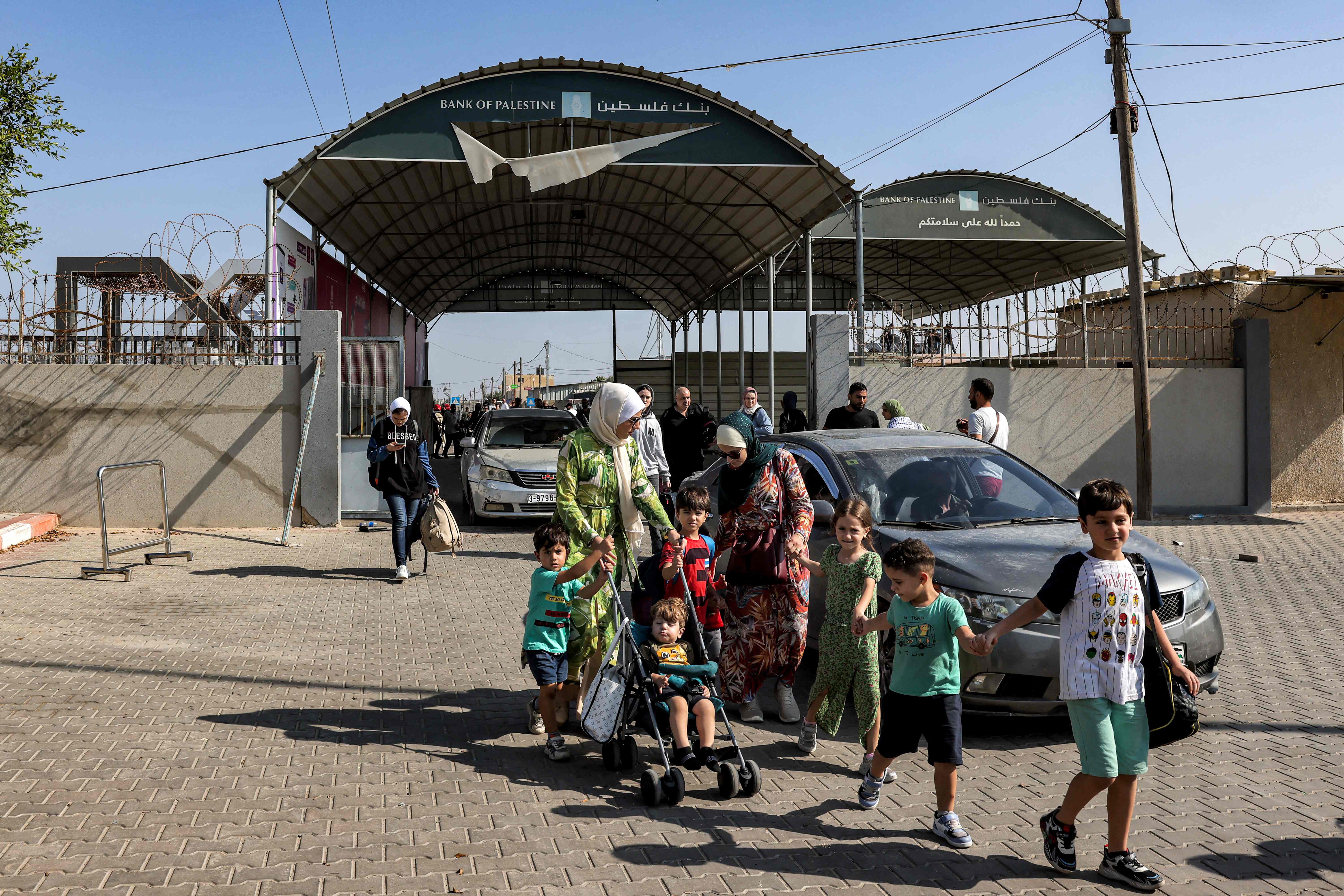 People enter the Rafah border crossing in the southern Gaza Strip before crossing into Egypt on 1 November 2023. Scores of foreign passport holders trapped in Gaza started leaving the war-torn Palestinian territory on November 1 when the Rafah crossing to Egypt was opened up for the first time since the 7 October Hamas attacks on Israel, according to AFP correspondents