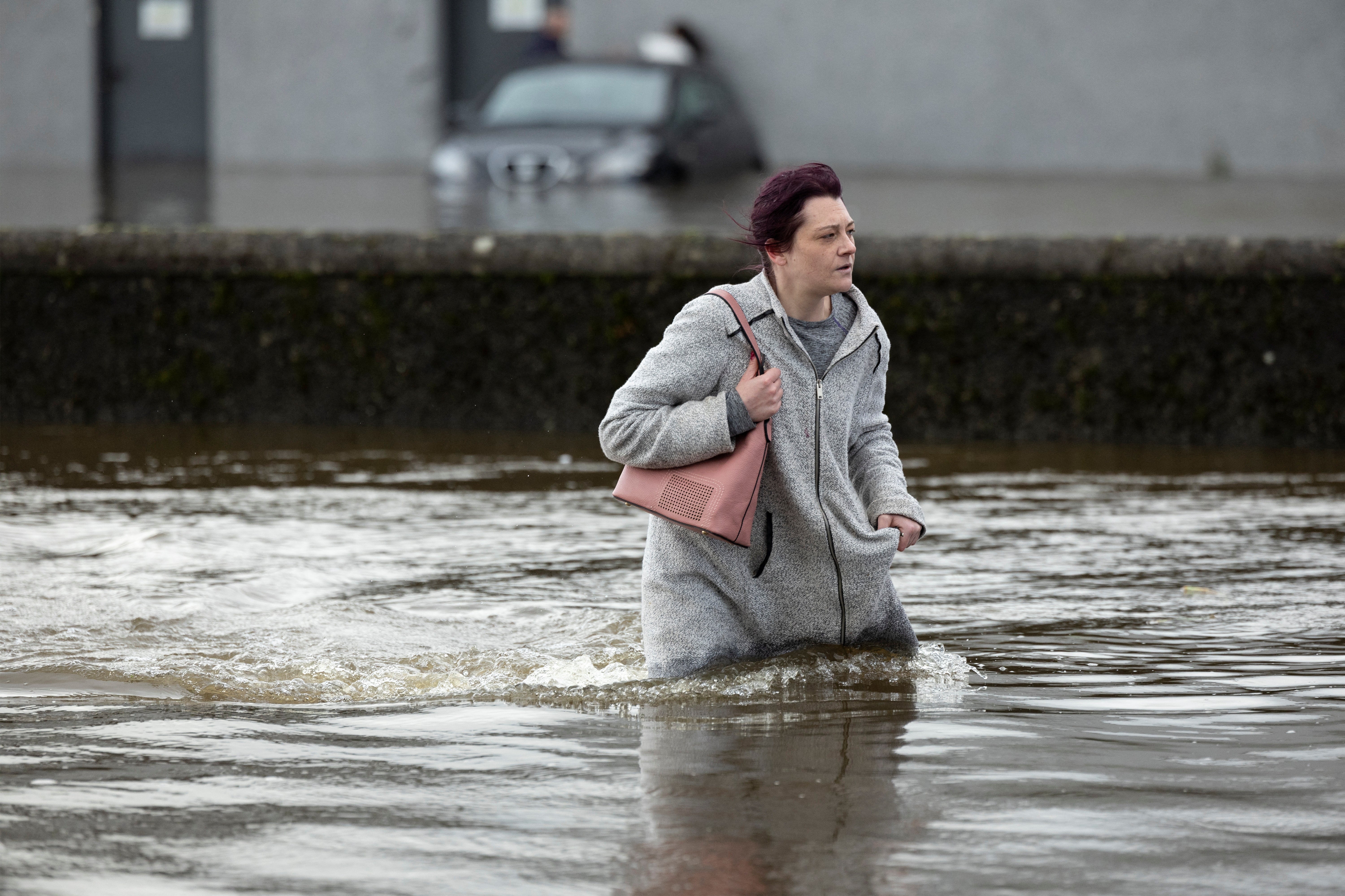 A woman tries to walk through water as it flows through the streets after heavy rain caused extensive flooding in Ireland