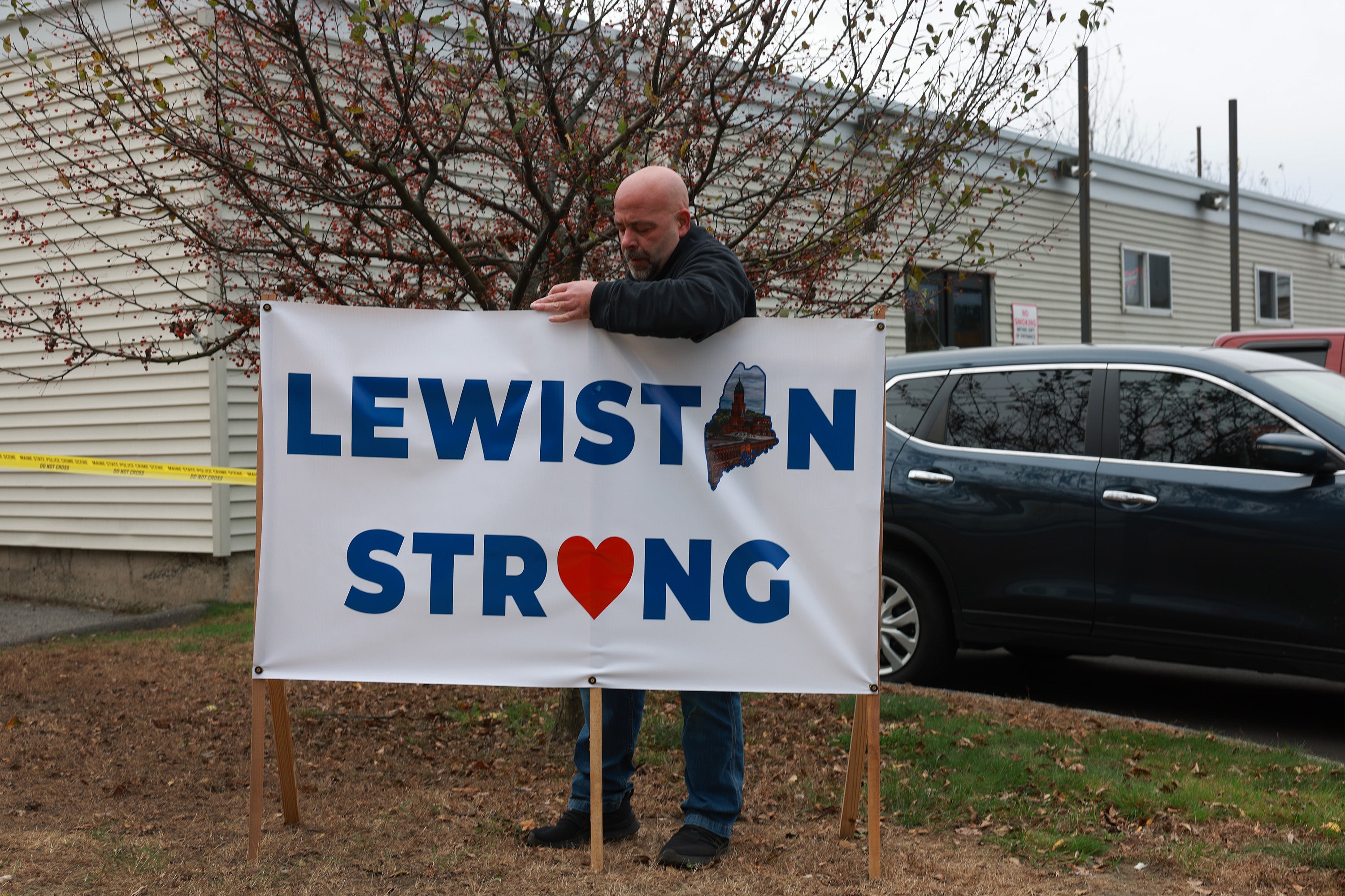 A resident places a Lewiston Strong sign outside of the Schemengees Bar