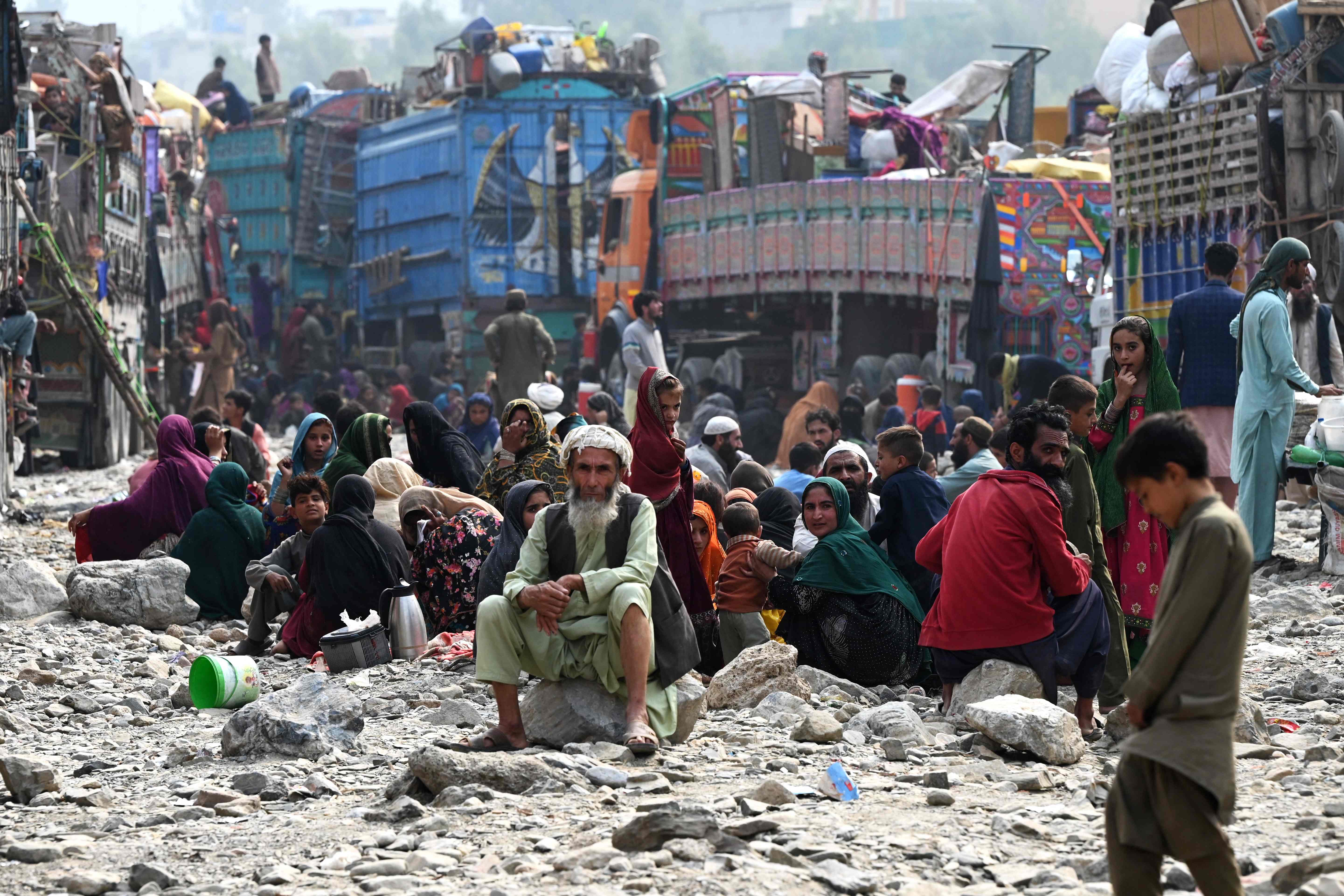 Afghan refugees rest near trucks upon their arrival from Pakistan at the Afghanistan-Pakistan Torkham border in Nangarhar province on November 1, 2023.