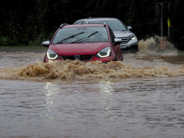 <p>Vehicles are driven through a flooded road in Yapton, West Sussex, as Storm Ciaran brings high winds and heavy rain</p>