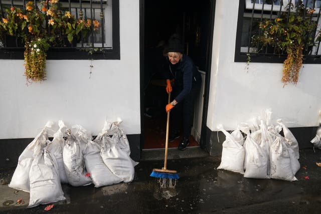 Delia Magee sweeps up outside Magee’s Bar, which has been in her husband’s family since 1913, as the clear up begins in Newry Town, Co Down (Brian Lawless/PA)