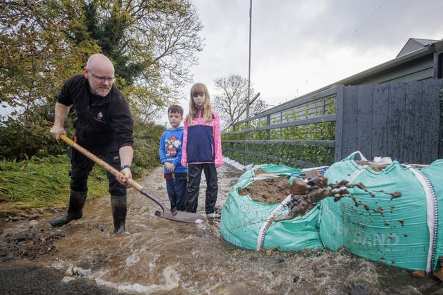 Damien McShane with his son Ryan and daughter Maevh clear a path to their house on the outskirts of Carlingford (Liam McBurney/PA)