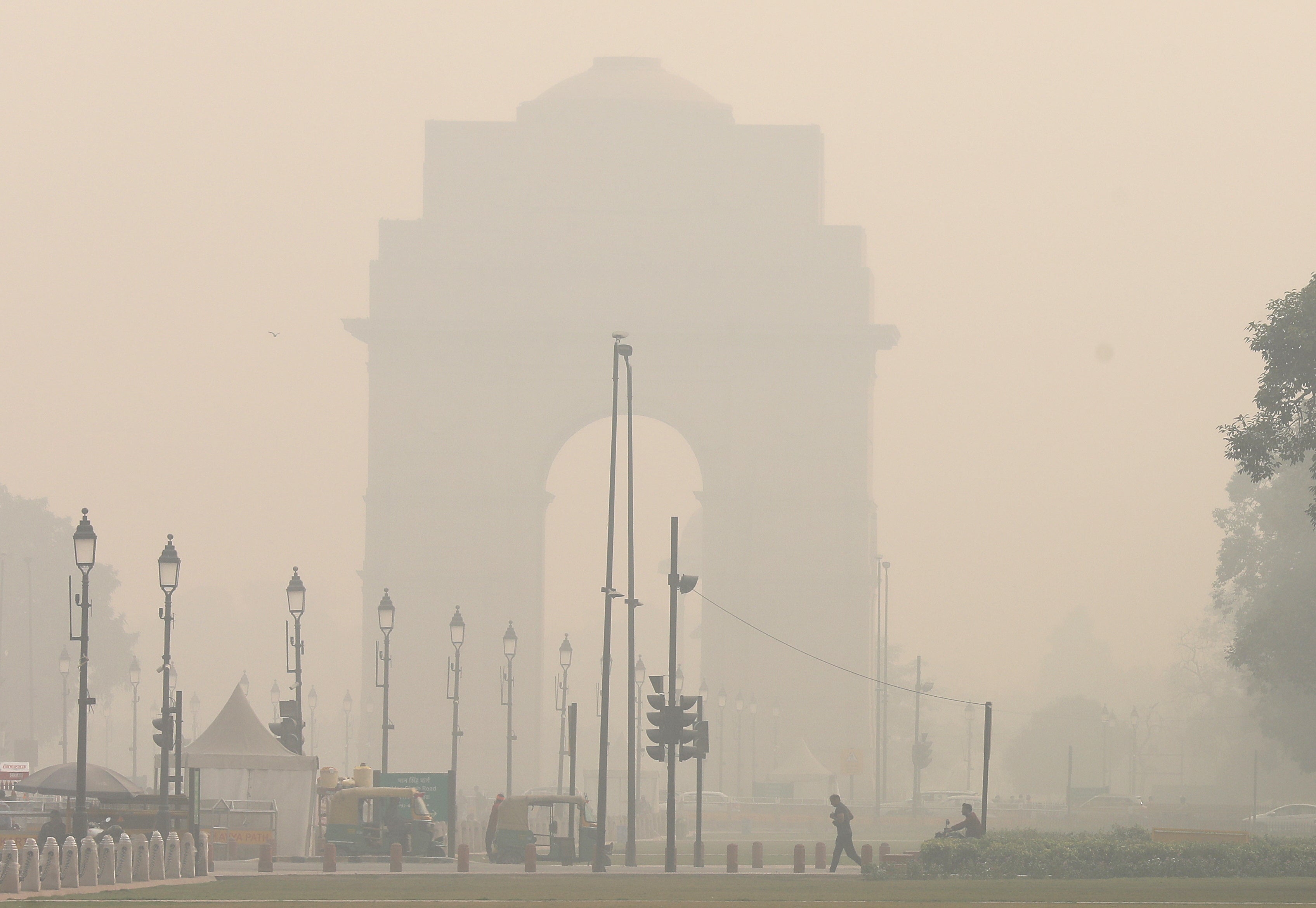Pedestrians cross a street as the city is engulfed in heavy smog at Rajpath, in New Delhi