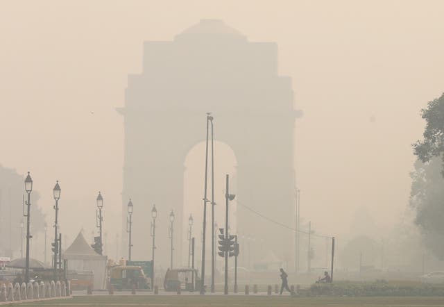 <p>Pedestrians cross a street as the city is engulfed in heavy smog at Rajpath in Delhi </p>