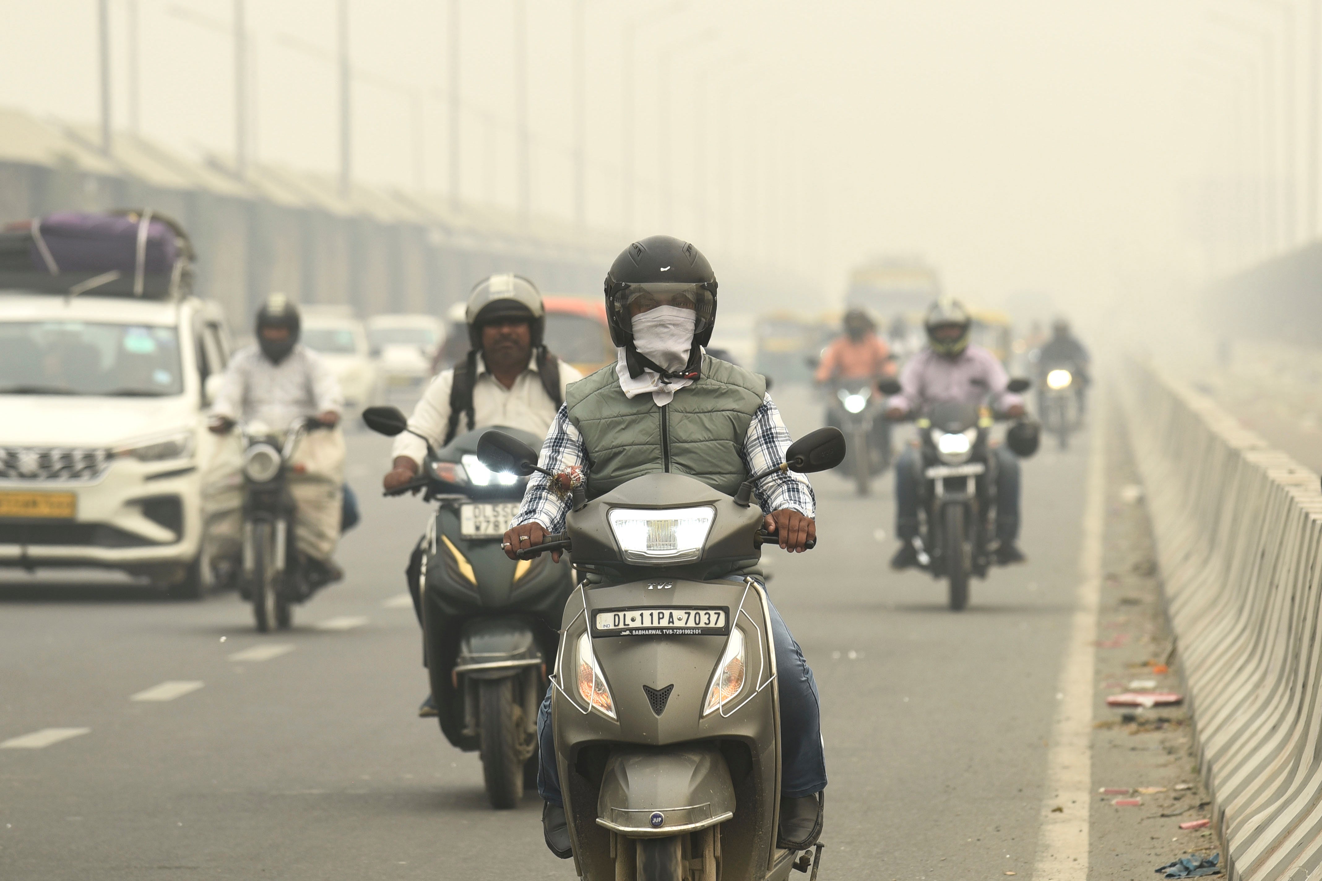 Traffic moves on a road enveloped by fog and smog in New Delhi, India, Friday