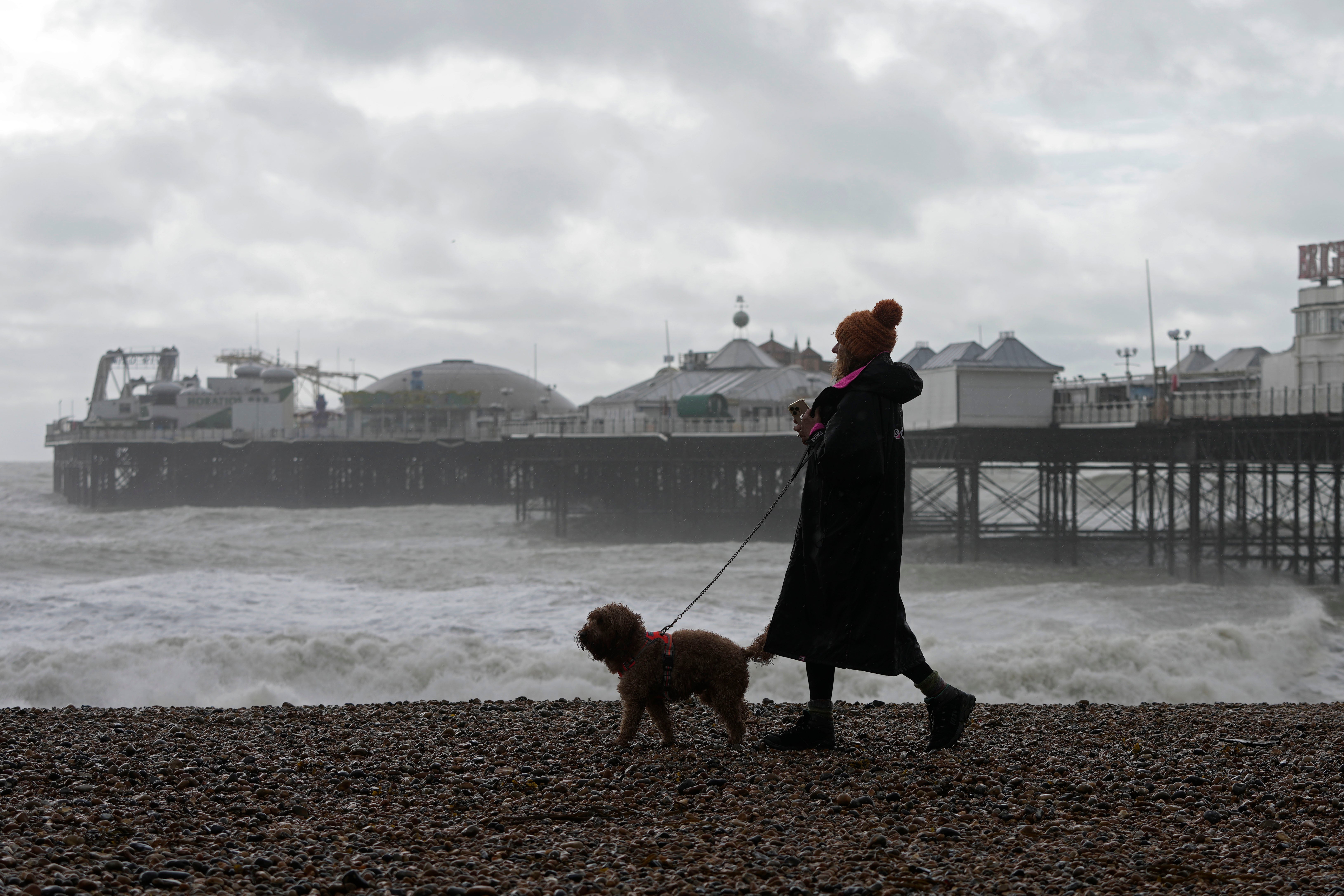 A woman walking her dog as Storm Ciarán hit Brighton beach