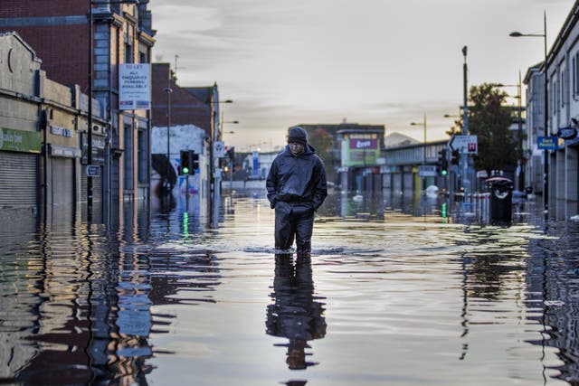 Michael McShane walks through flood water on Market Street in Downpatrick, Northern Ireland (Liam McBurney/PA)