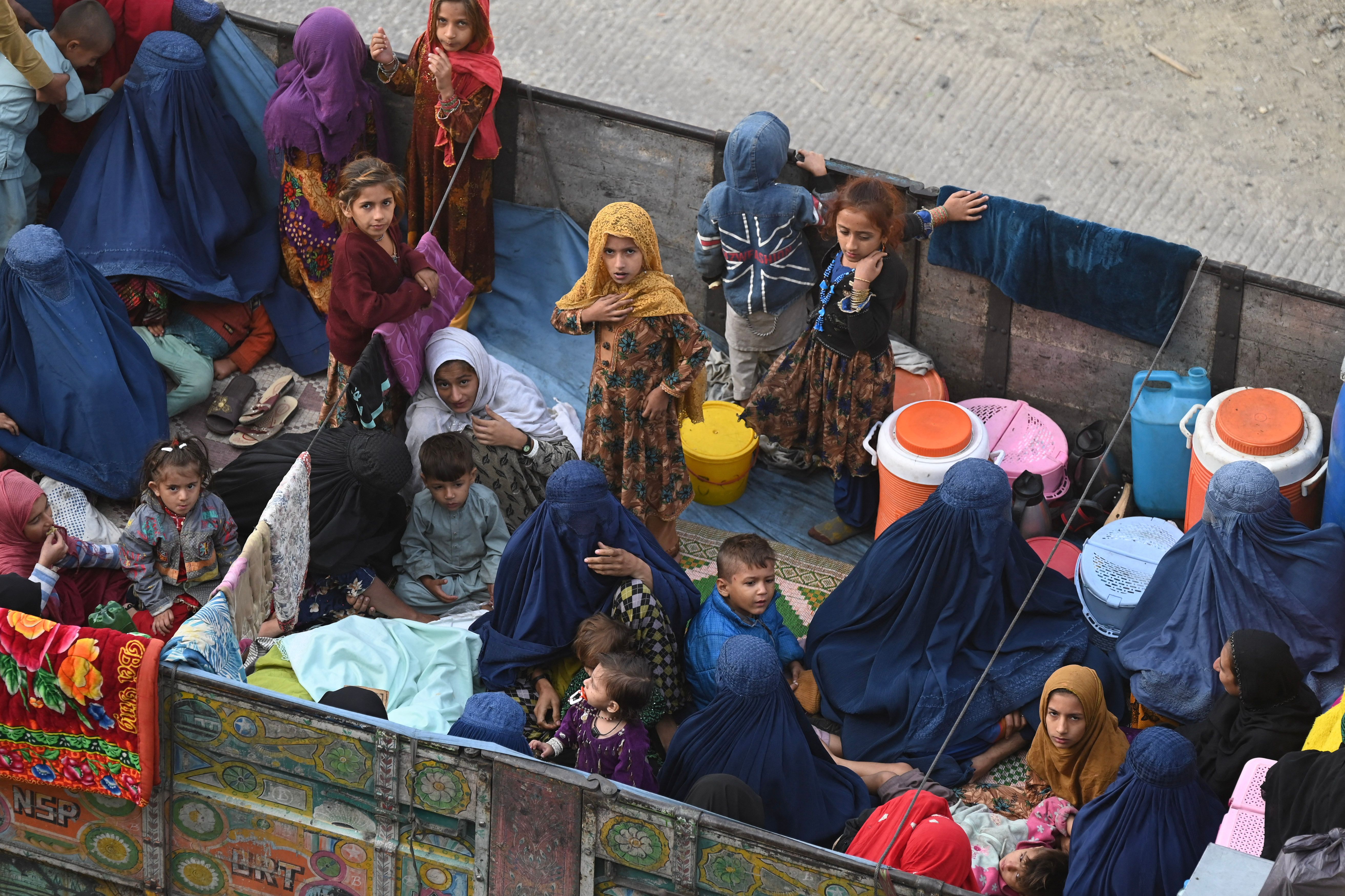 Afghan refugee families sit on a truck heading towards the Pakistan-Afghanistan Torkham border