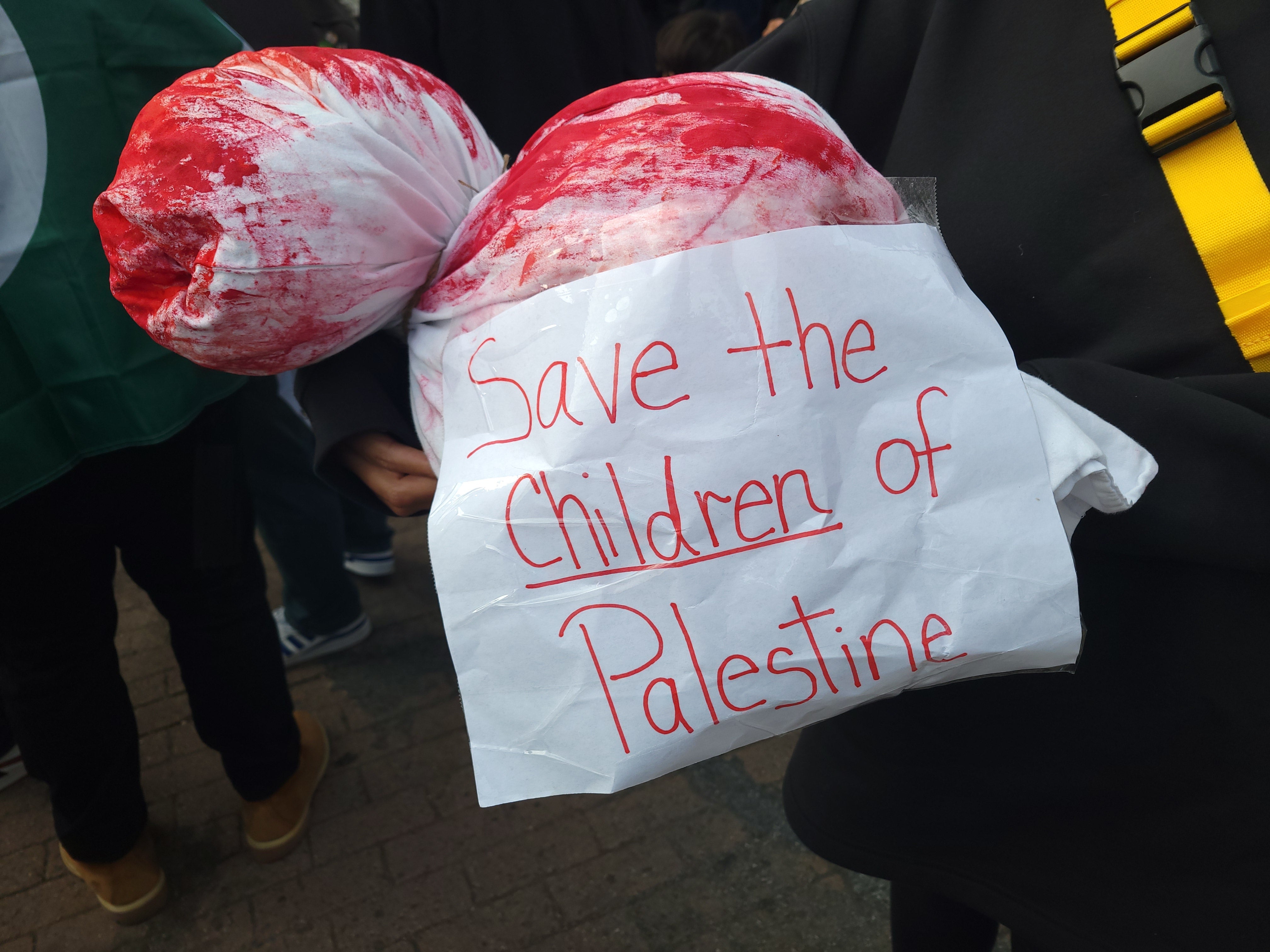 A woman carries an object meant to depict the bloody corpse of a child at DC’s March for Palestine on Saturday