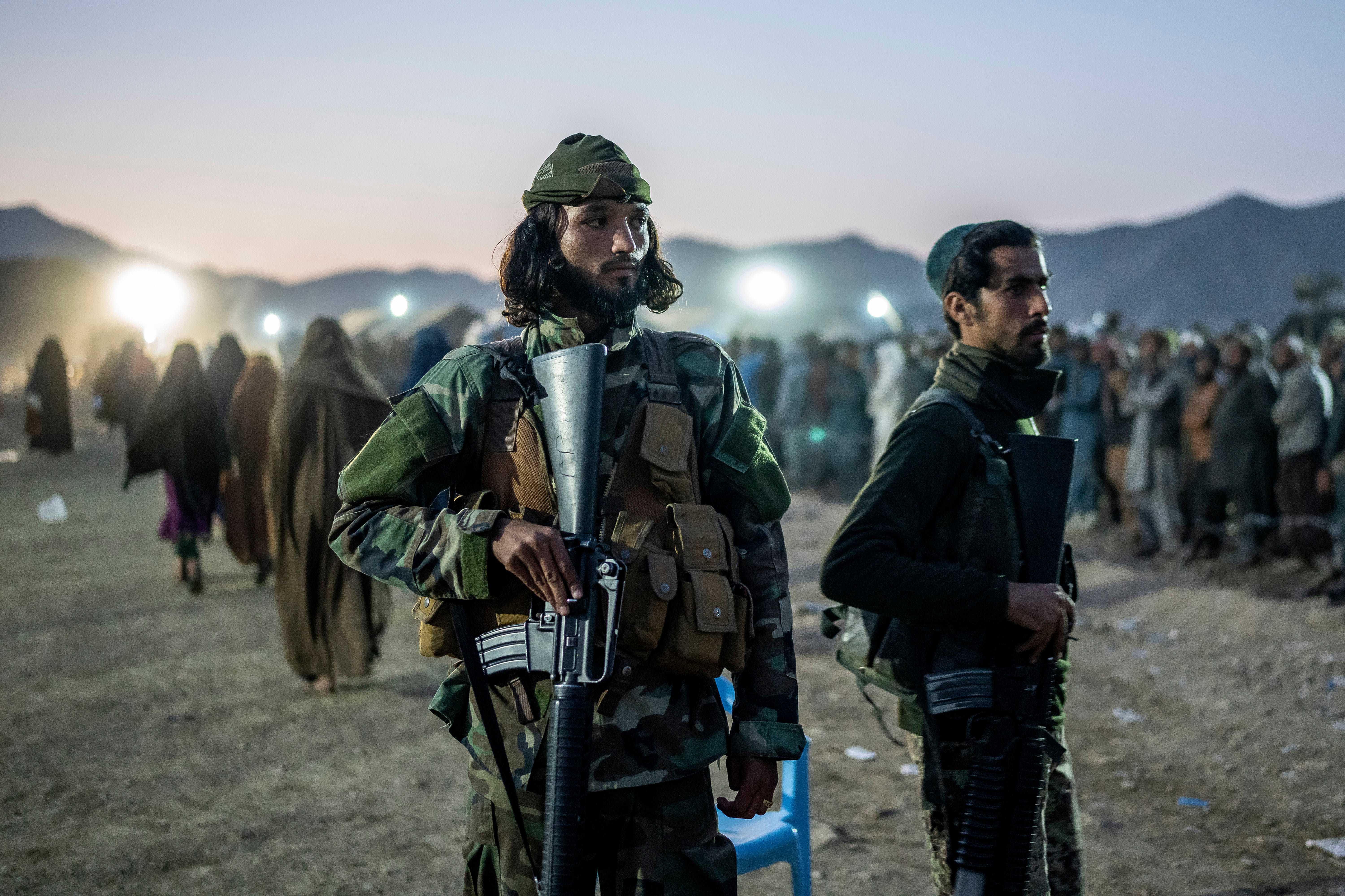 Taliban fighters stand guard as Afghan refugees line up to register in a camp near the Torkham Pakistan-Afghanistan border