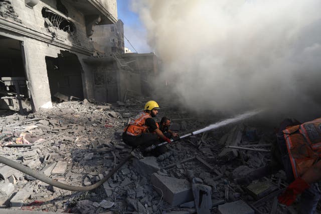 Palestinian firefighters extinguish a fire caused by an Israeli air strike in Gaza City (Abed Khaled/AP)