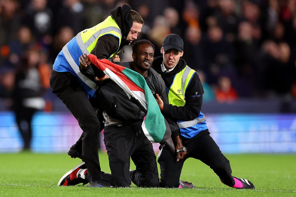 Pitch invader with Palestine flag disrupts match after Luton score against Liverpool Pitch invader with Palestine flag disrupts match after Luton score against Liverpool