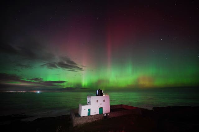 The aurora borealis, also known as the northern lights were seen over Bamburgh Lighthouse (Owen Humphreys/PA)