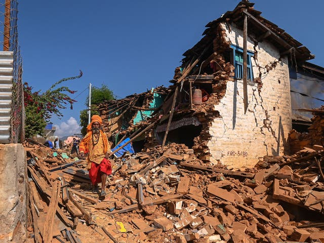 <p>A Hindu holyman walks through the ruins of a damaged house following an earthquake in Khalanga, Nepal</p>