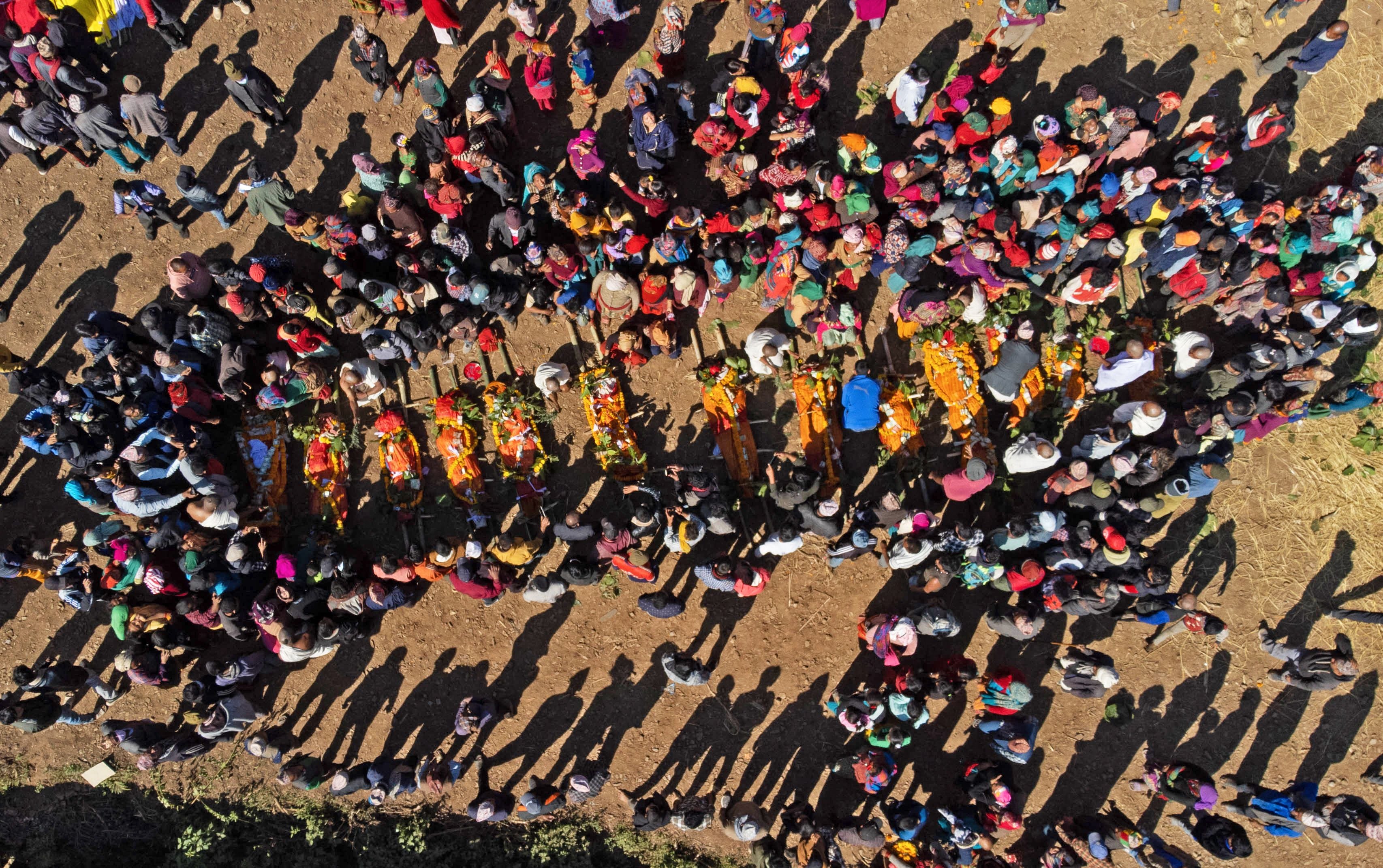 An aerial view shows family members and villagers gathered around the bodies of earthquake victims