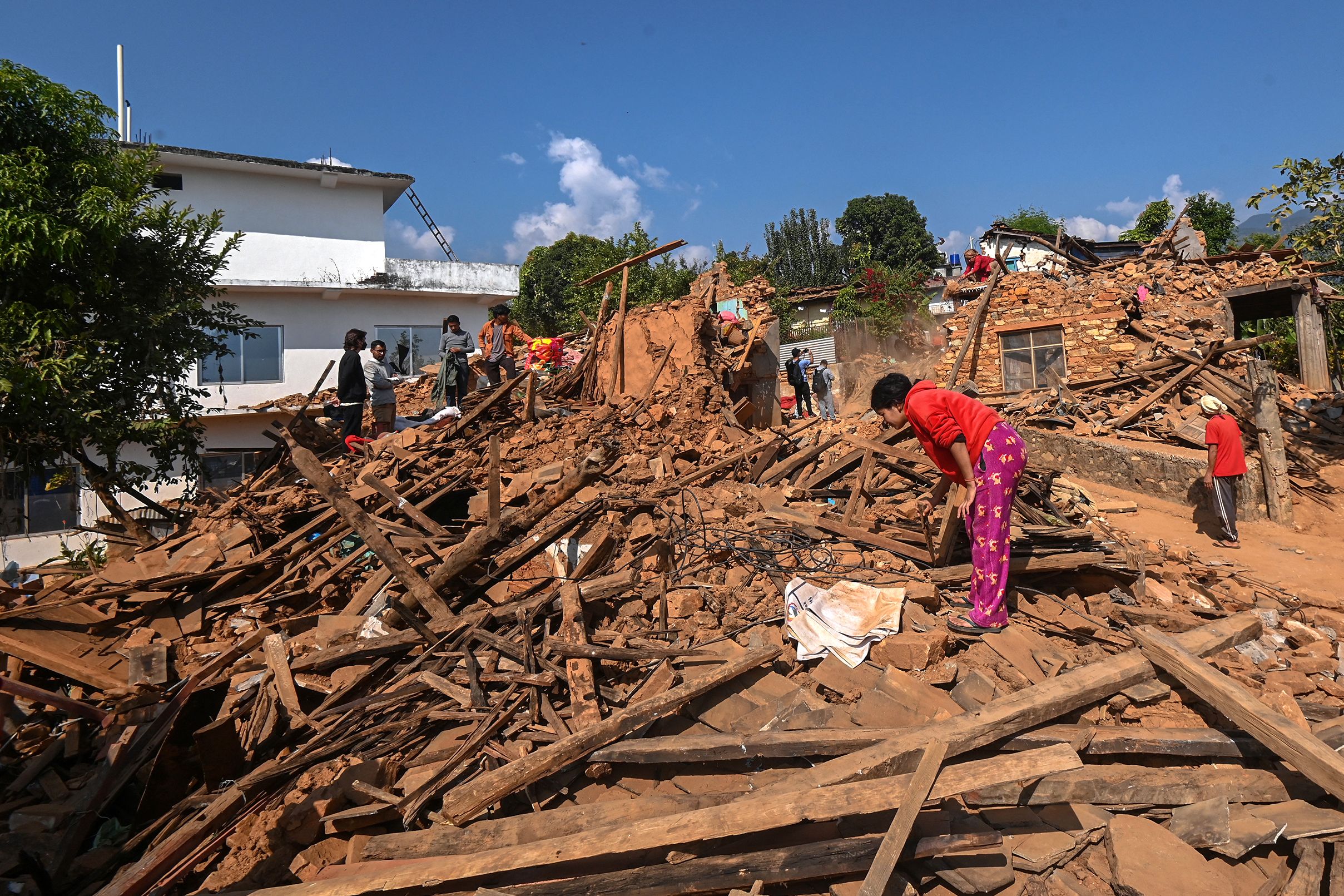 Survivors search for their belongings through the ruins of damaged houses following an earthquake in Khalanga of Jajarkot district, Nepal