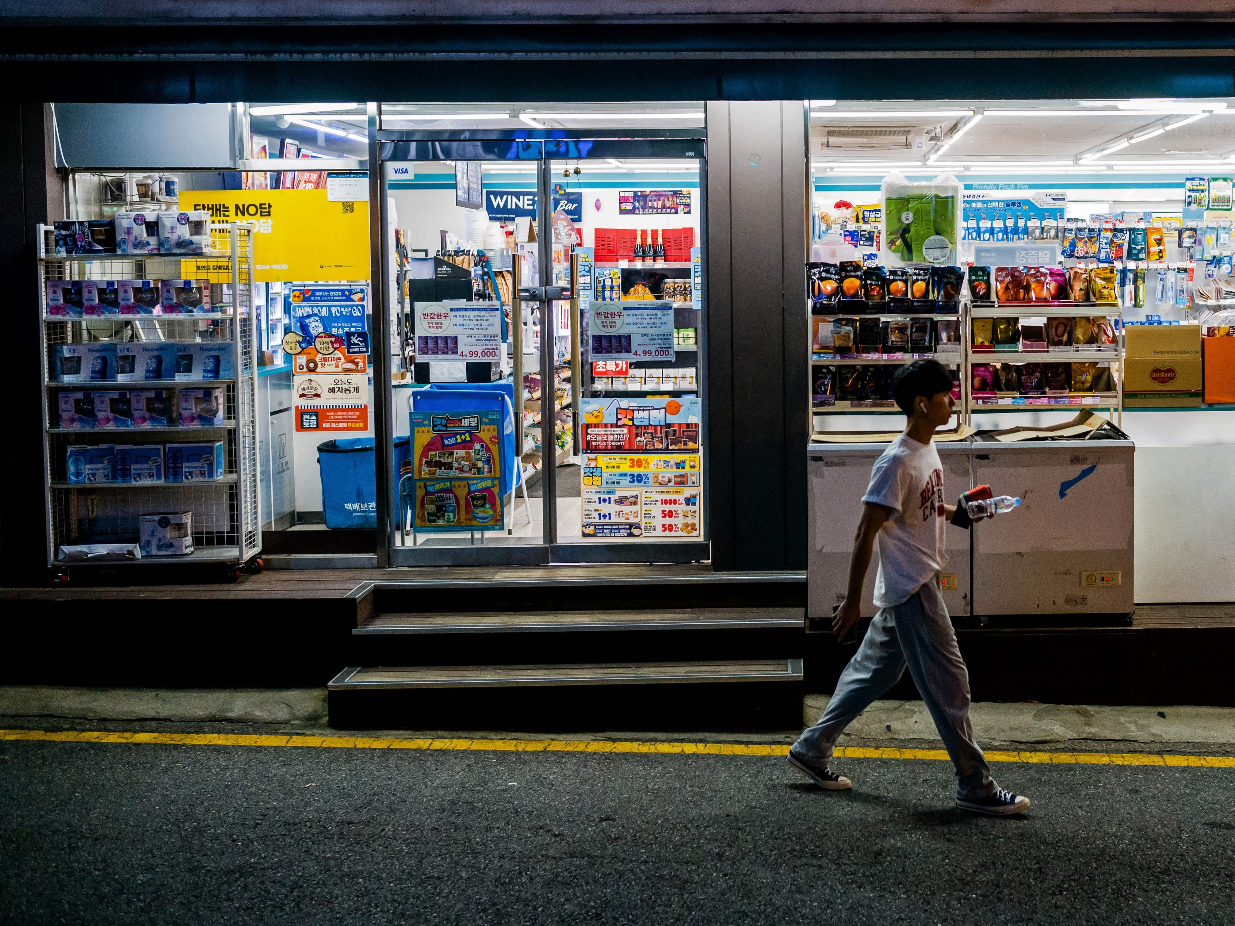 <p>A man walks past a convenience store along a street in Seoul. Representational</p>