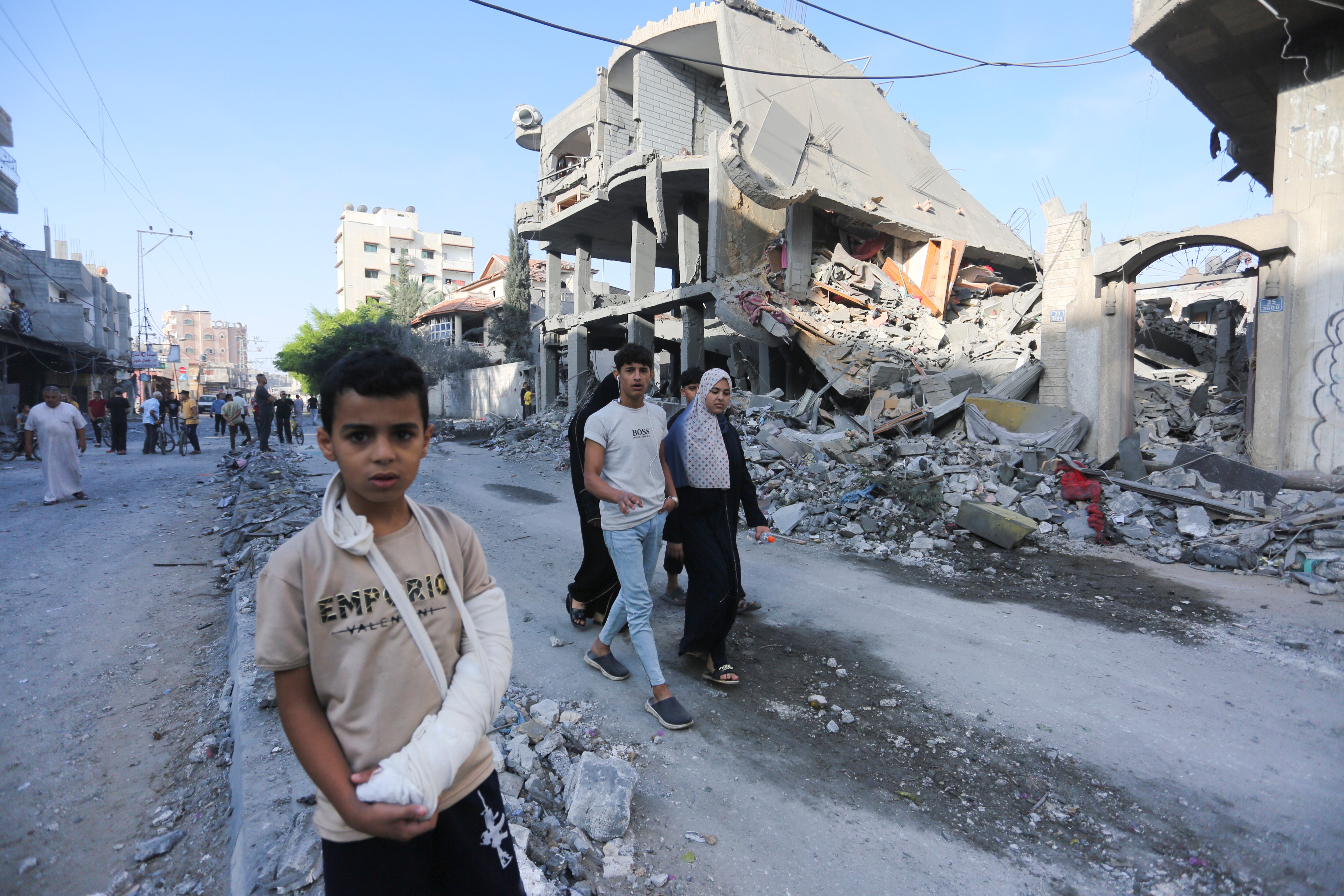 Palestinians walk by buildings destroyed in the Israeli bombardment of the Gaza Strip in Rafah on Tuesday