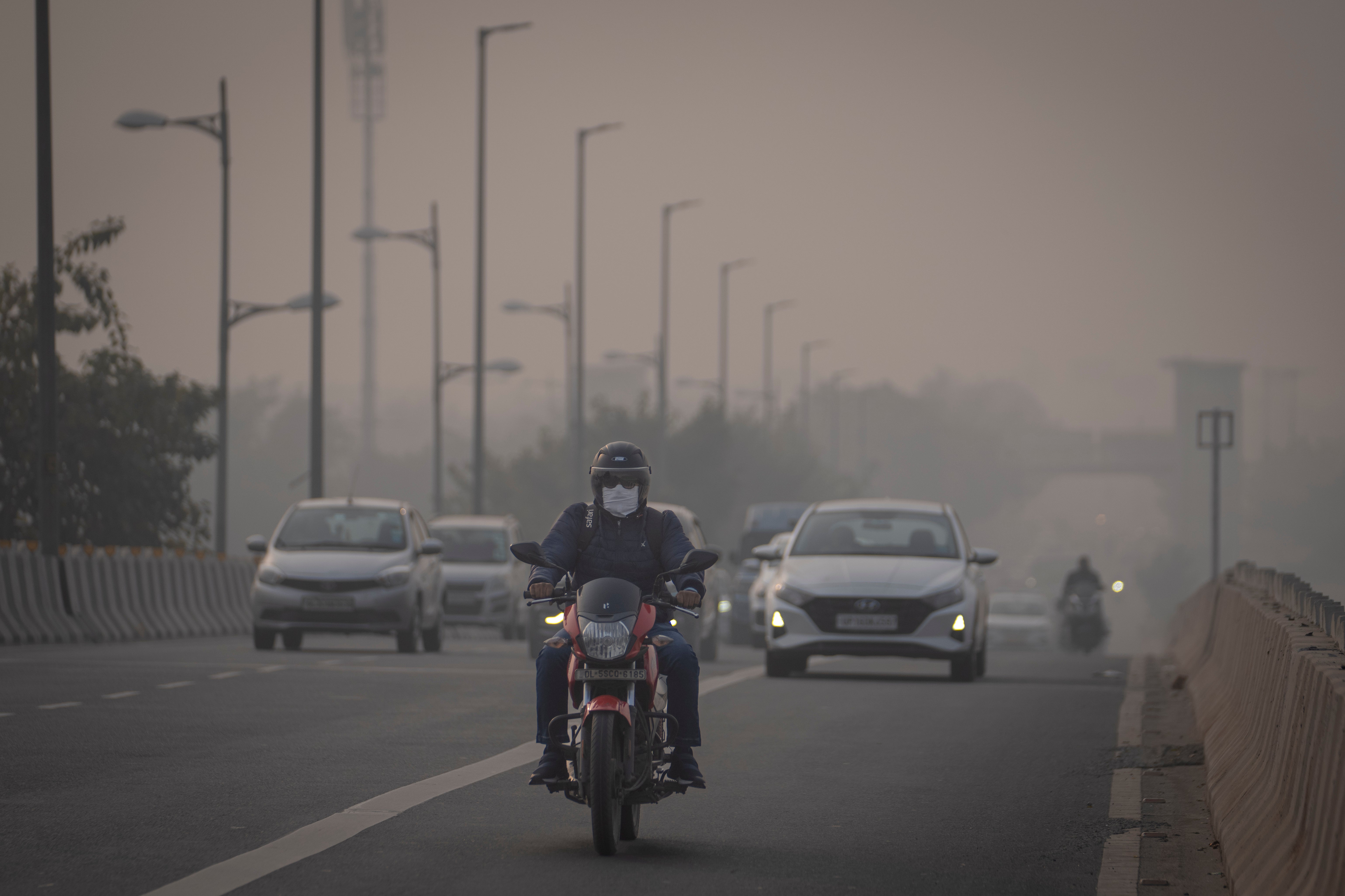 A motorcyclist wearing a pollution mask drives through smog in Delhi