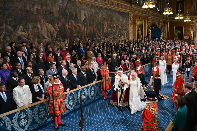 The King, wearing the Imperial State Crown and the Robe of State, and the Queen, wearing the George IV State Diadem, pass through the Royal Gallery (Justin Tallis/PA)