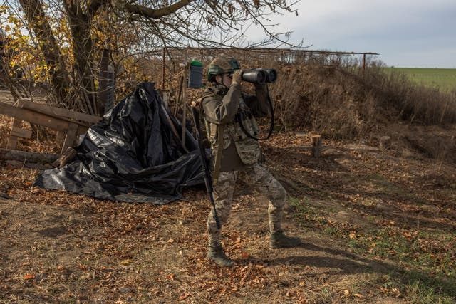 <p>A Ukrainian military member checks the area with binoculars at a position outside the southern city of Kherson</p>