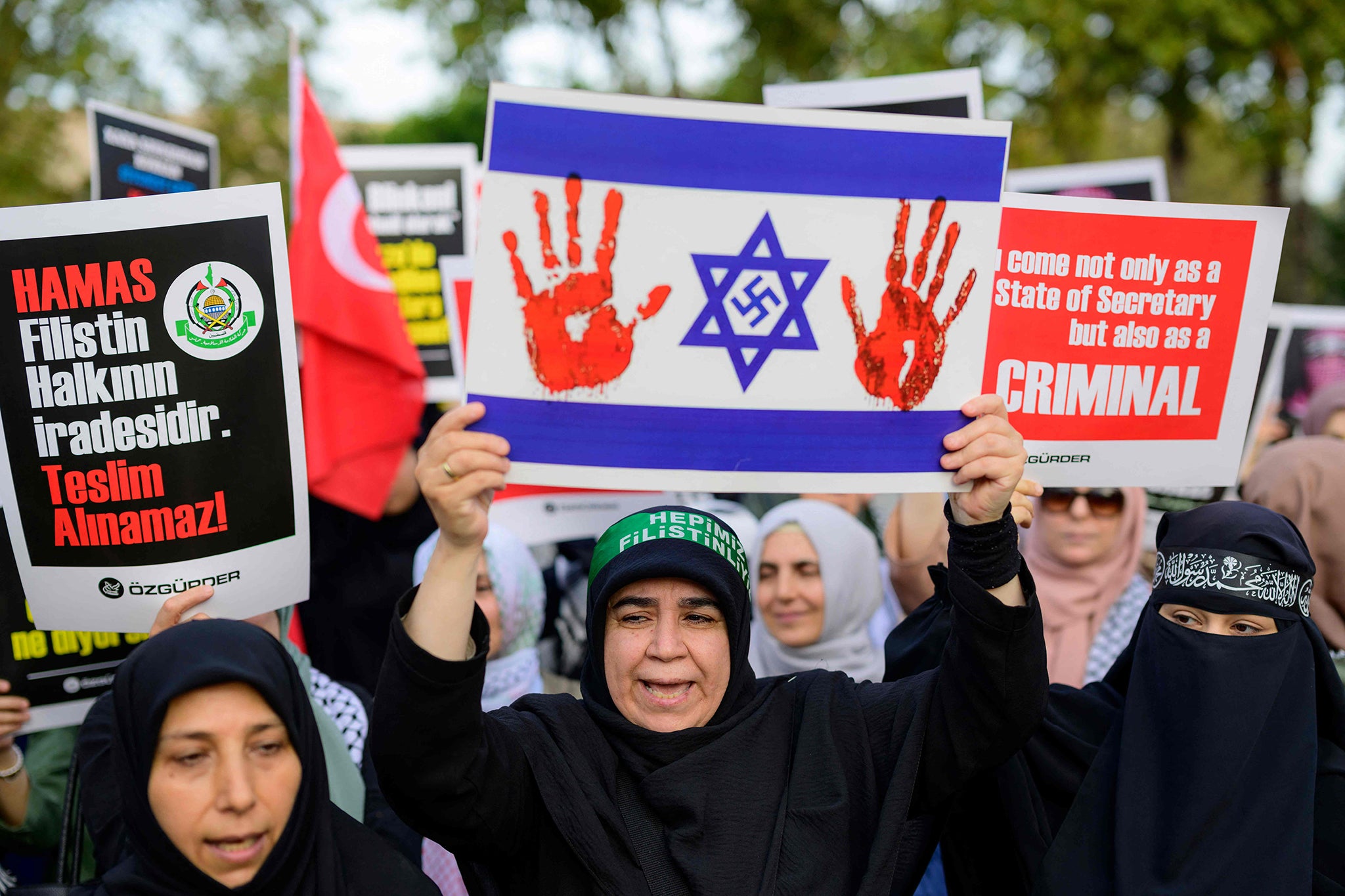 Pro-Palestinian demonstrators hold slogans and a placard representing an Israeli flag with a Nazi swastika inside the Star of David as they take part in a rally against US secretary of state Antony Blinken’s visit to Turkey, in Istanbul