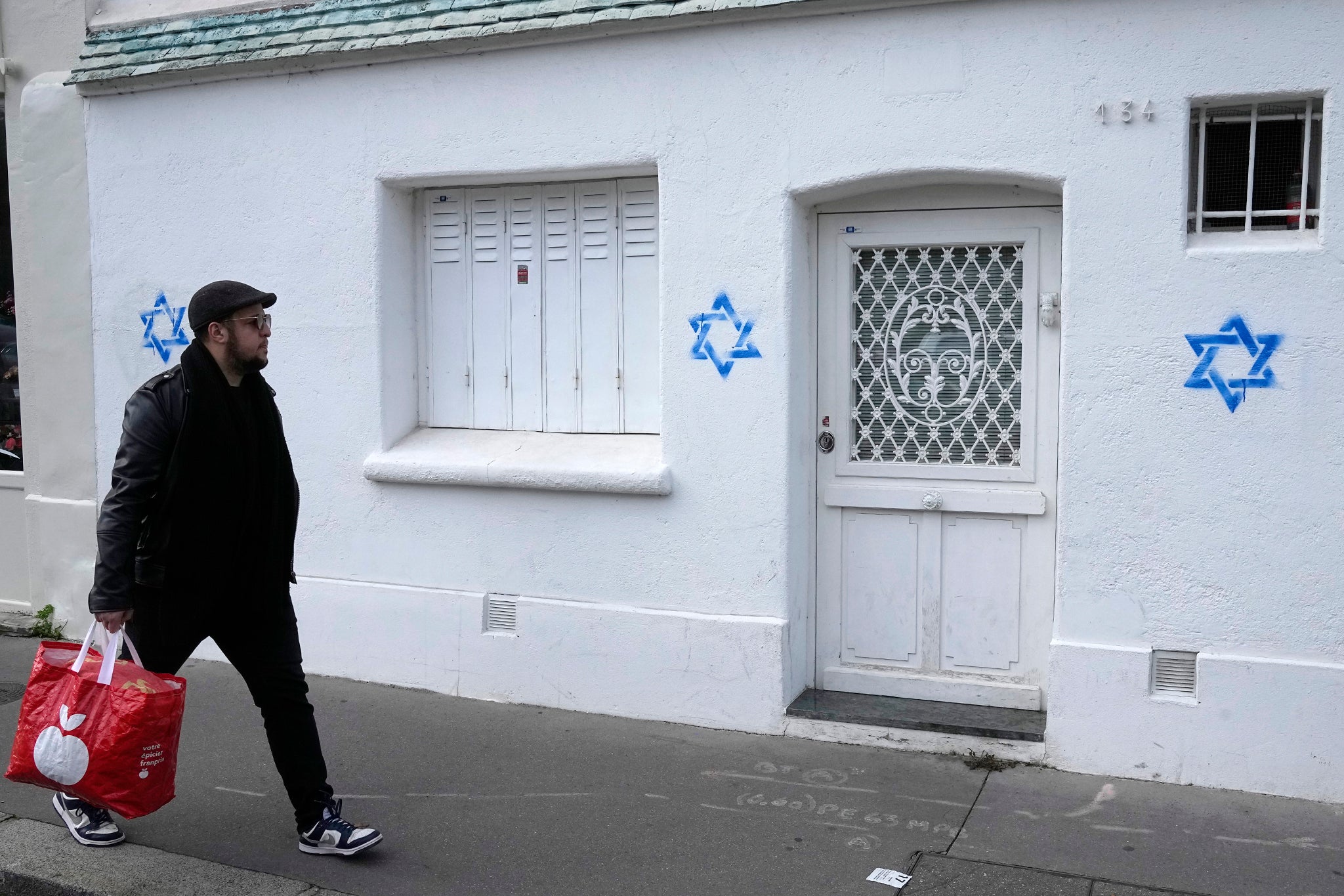 A man walks past Stars of David tagged on a wall in Paris. Paris police chief Laurent Nunez described the graffiti as antisemitic and said police are investigating