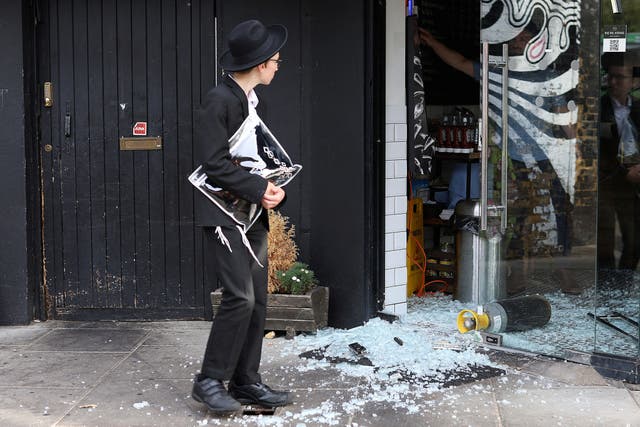 <p>A man looks at a vandalised Kosher restaurant in Golders Green, London, near a bridge with ‘Free Palestine’ painted on it</p>