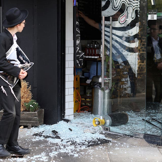 <p>A man looks at a vandalised kosher restaurant in Golders Green, London, near a bridge with ‘Free Palestine’ painted on it</p>