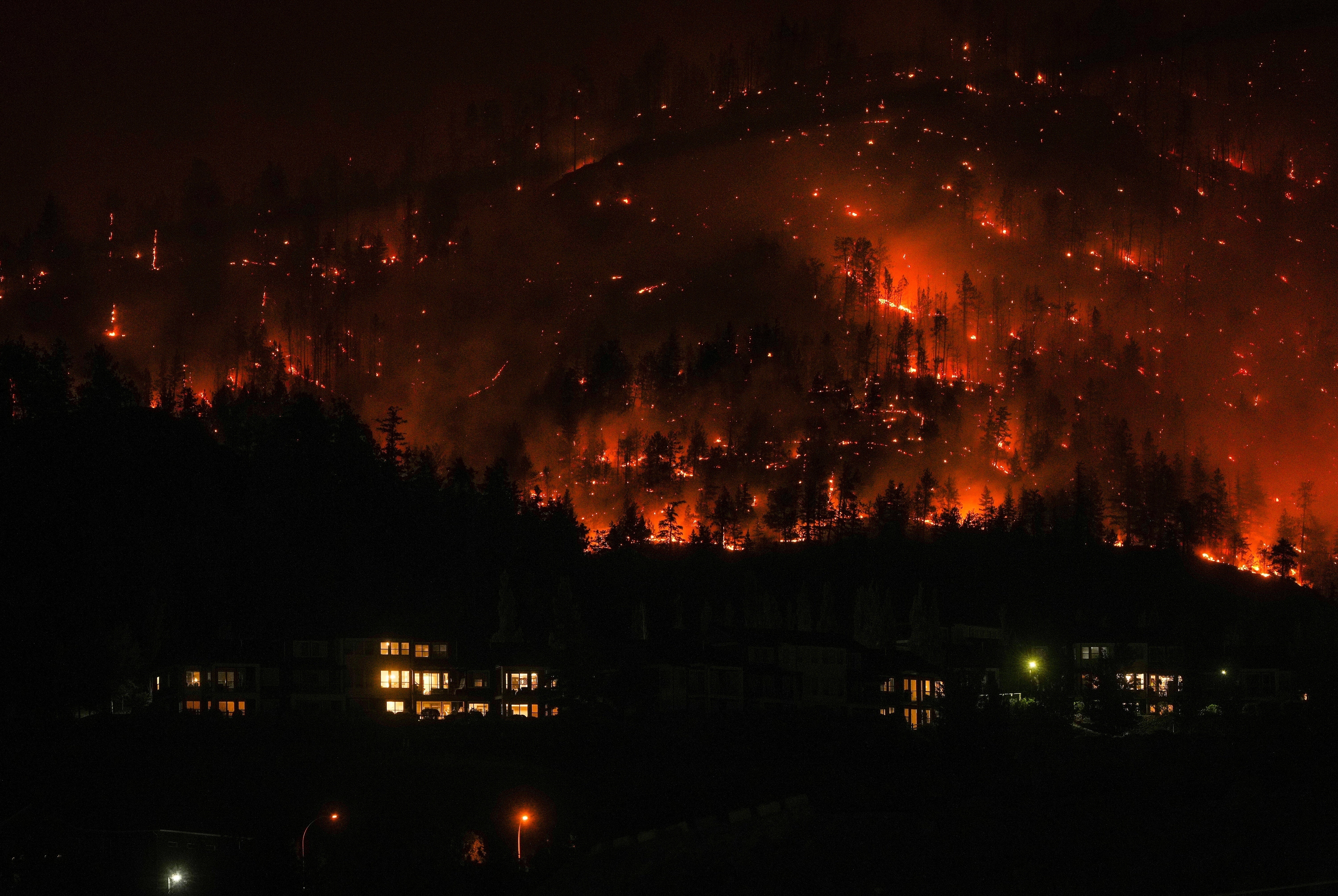 The McDougall Creek wildfire burns on the mountainside above houses in West Kelowna, British Columbia, on 18 August 2023