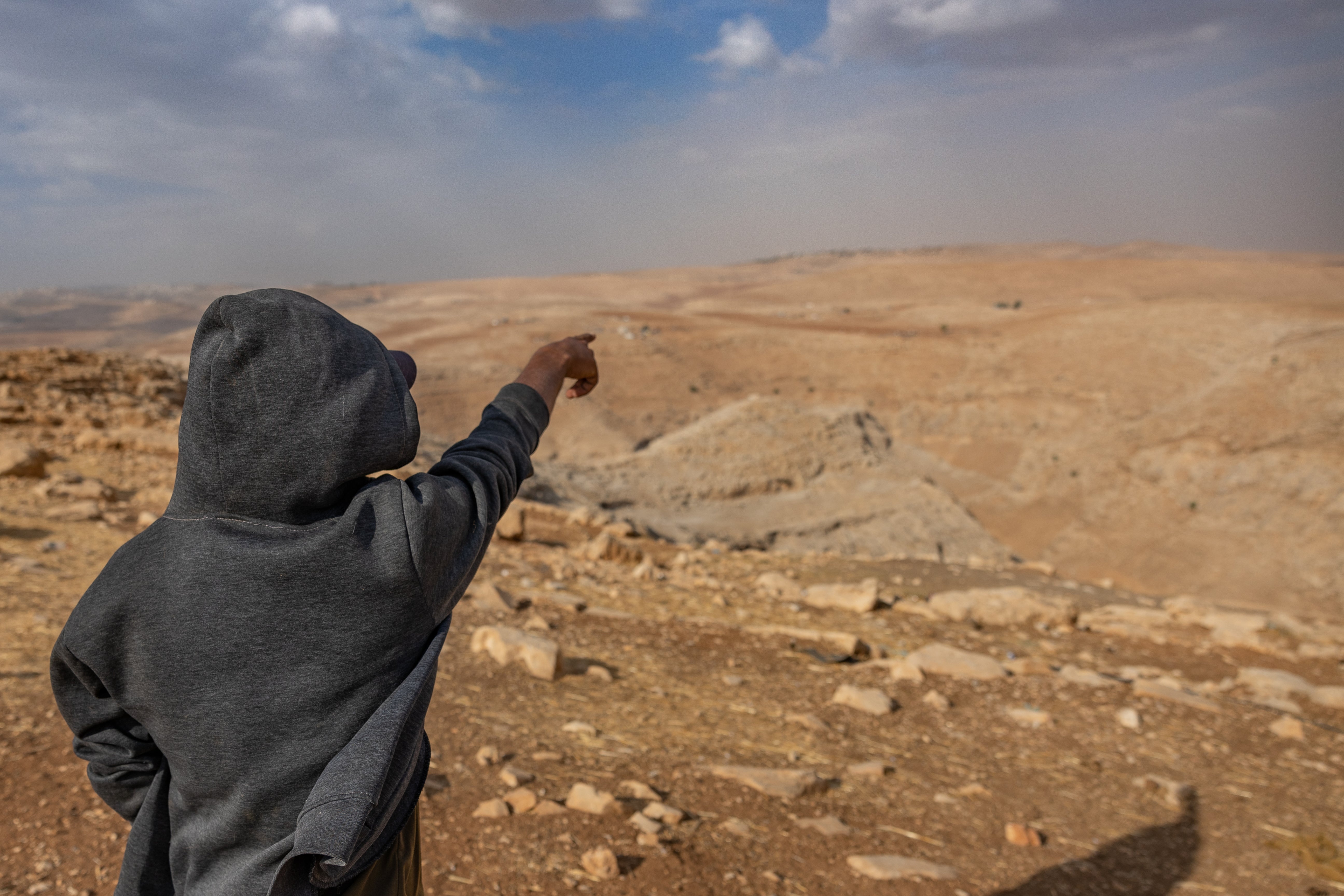 A man points towards Wadi al-Siq from the location where families have now been forced to stay