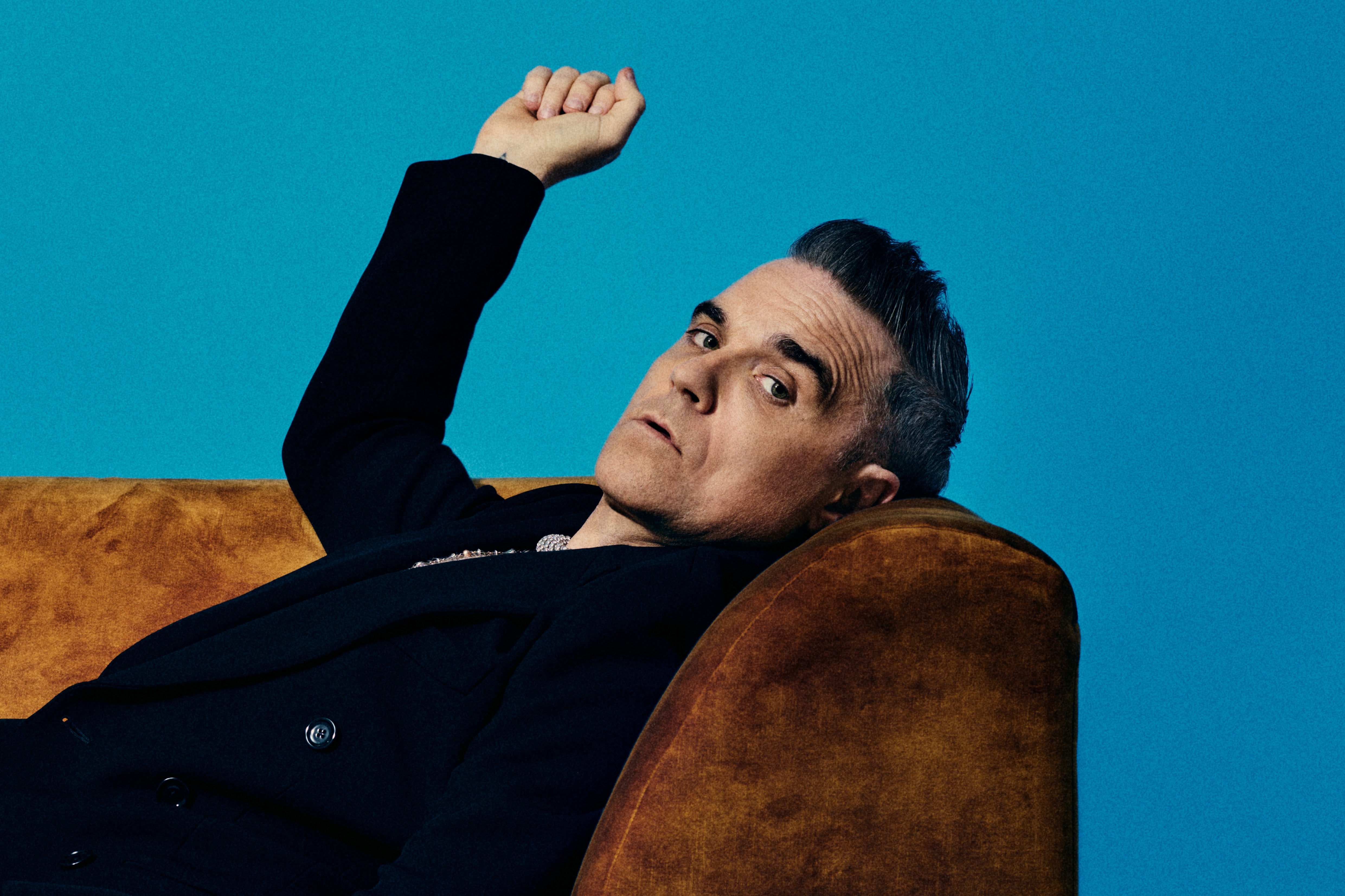Analyse That: Robbie Williams poses on a couch in a promotional photo for his new Netflix docuseries