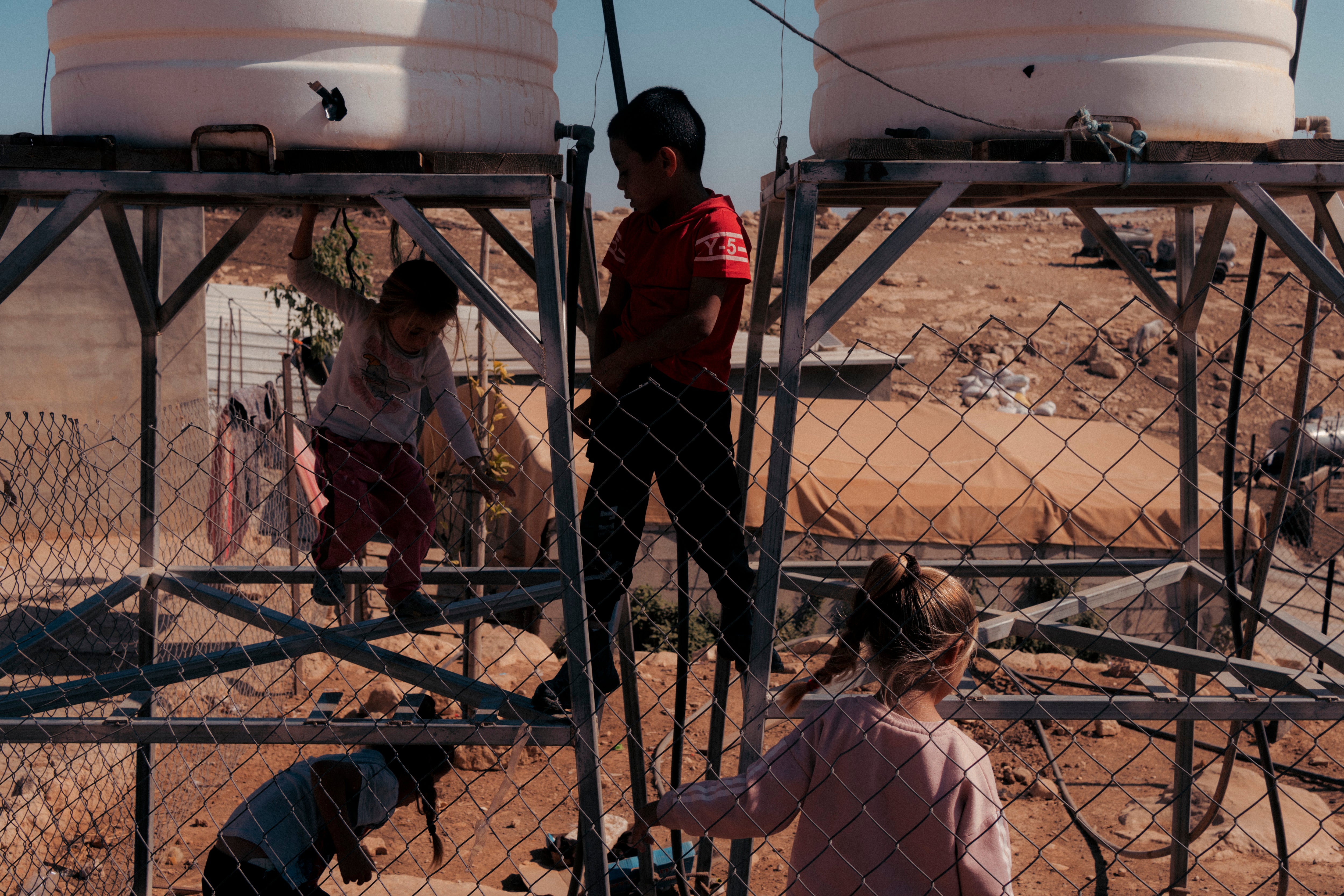 Children play around water tanks that were damaged by settlers during an attack in Tuba. Like many other communities in the South Hebron Hills, Tuba has often been attacked by settlers