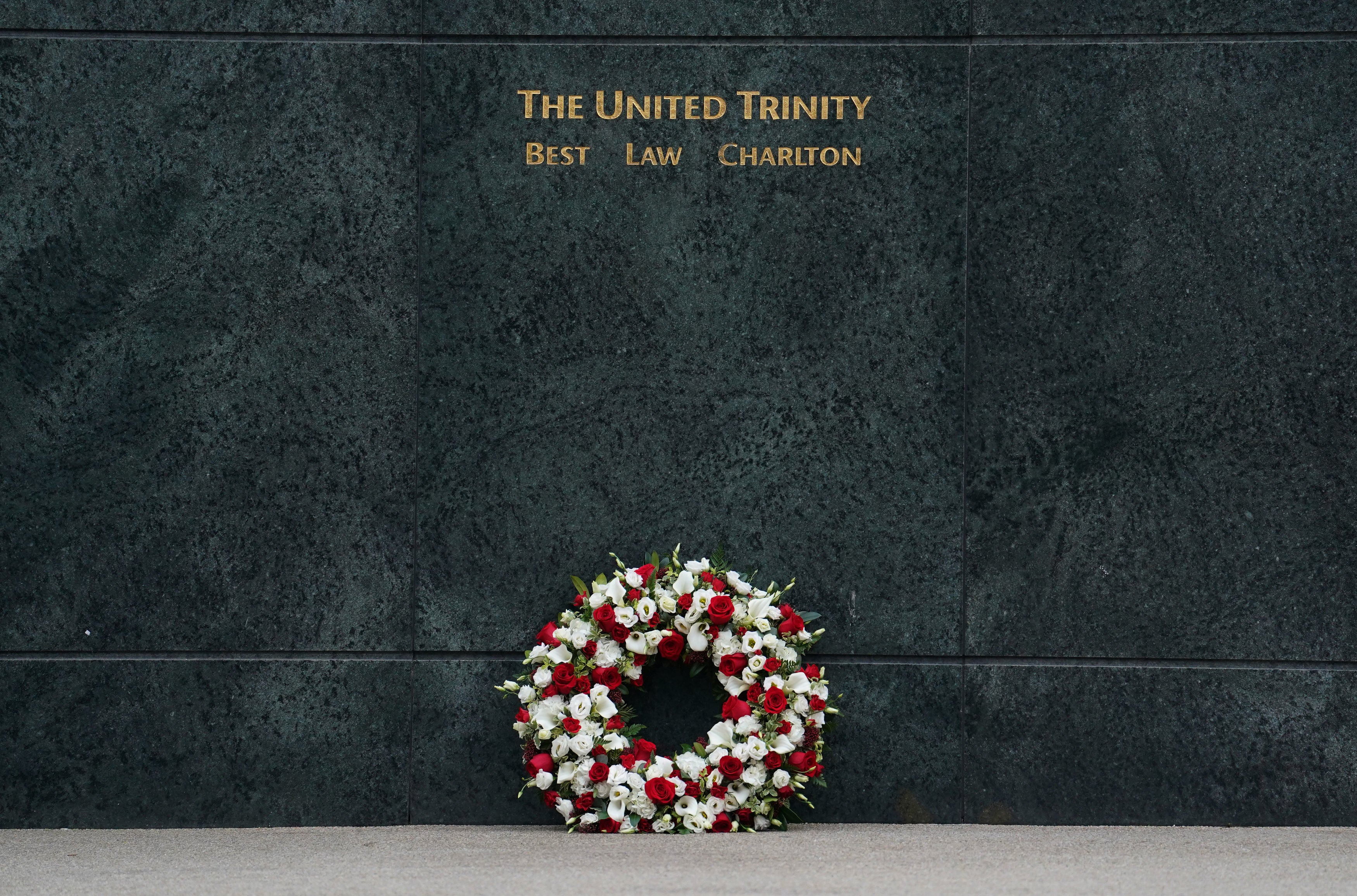 A wreath lies against the United Trinity statue