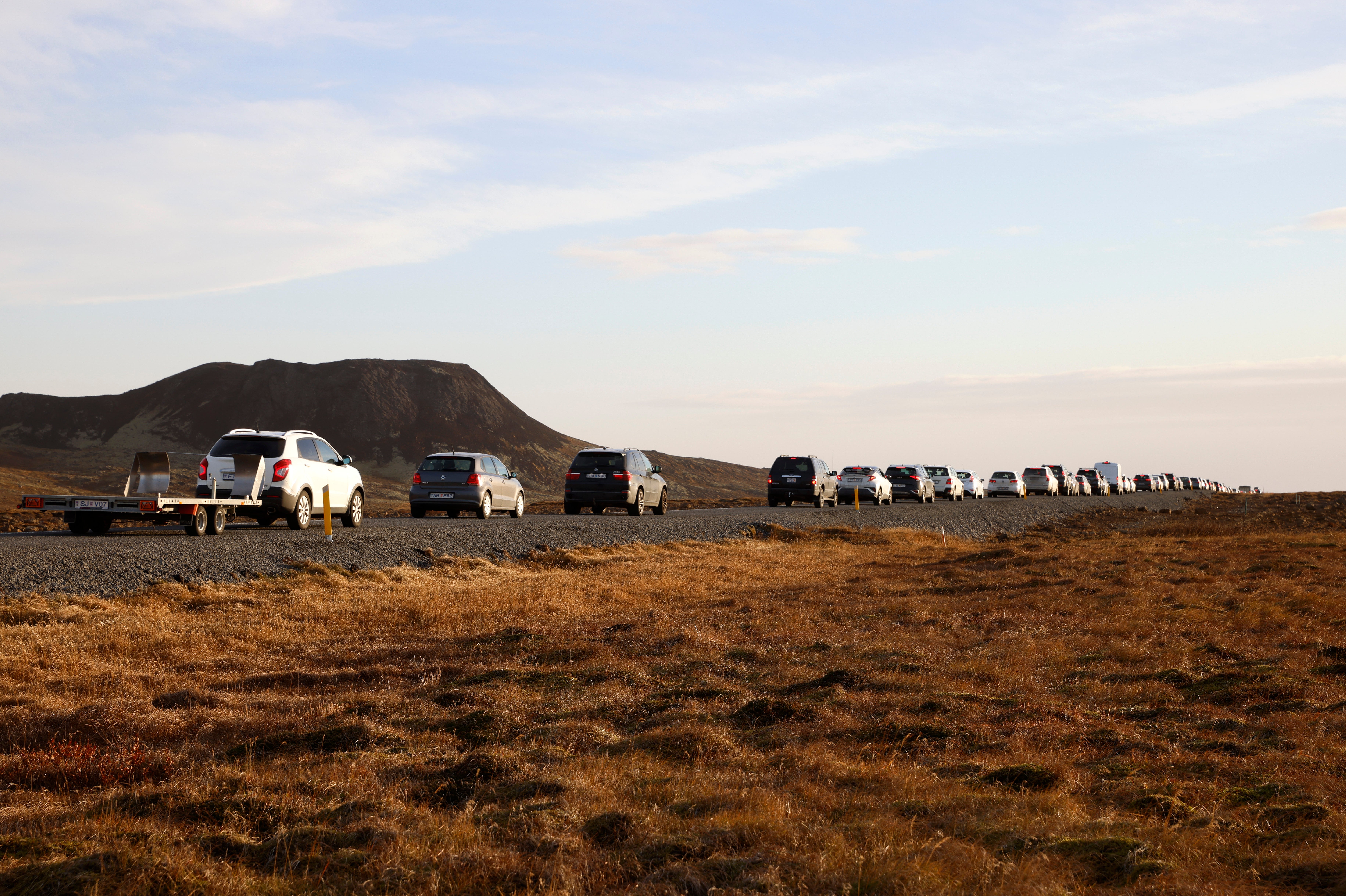 <p>A line of cars queued on a road heading to the town of Grindavik, Iceland on Monday as residents were briefly allowed to return to their homes</p>