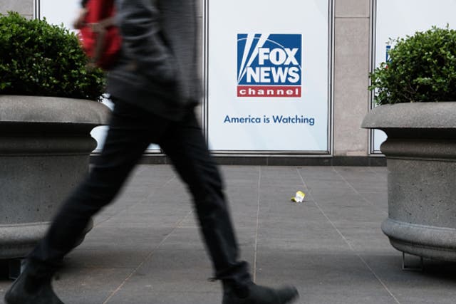 <p>People walk by the News Corporation headquarters, home to Fox News, on April 18, 2023 in New York City</p>